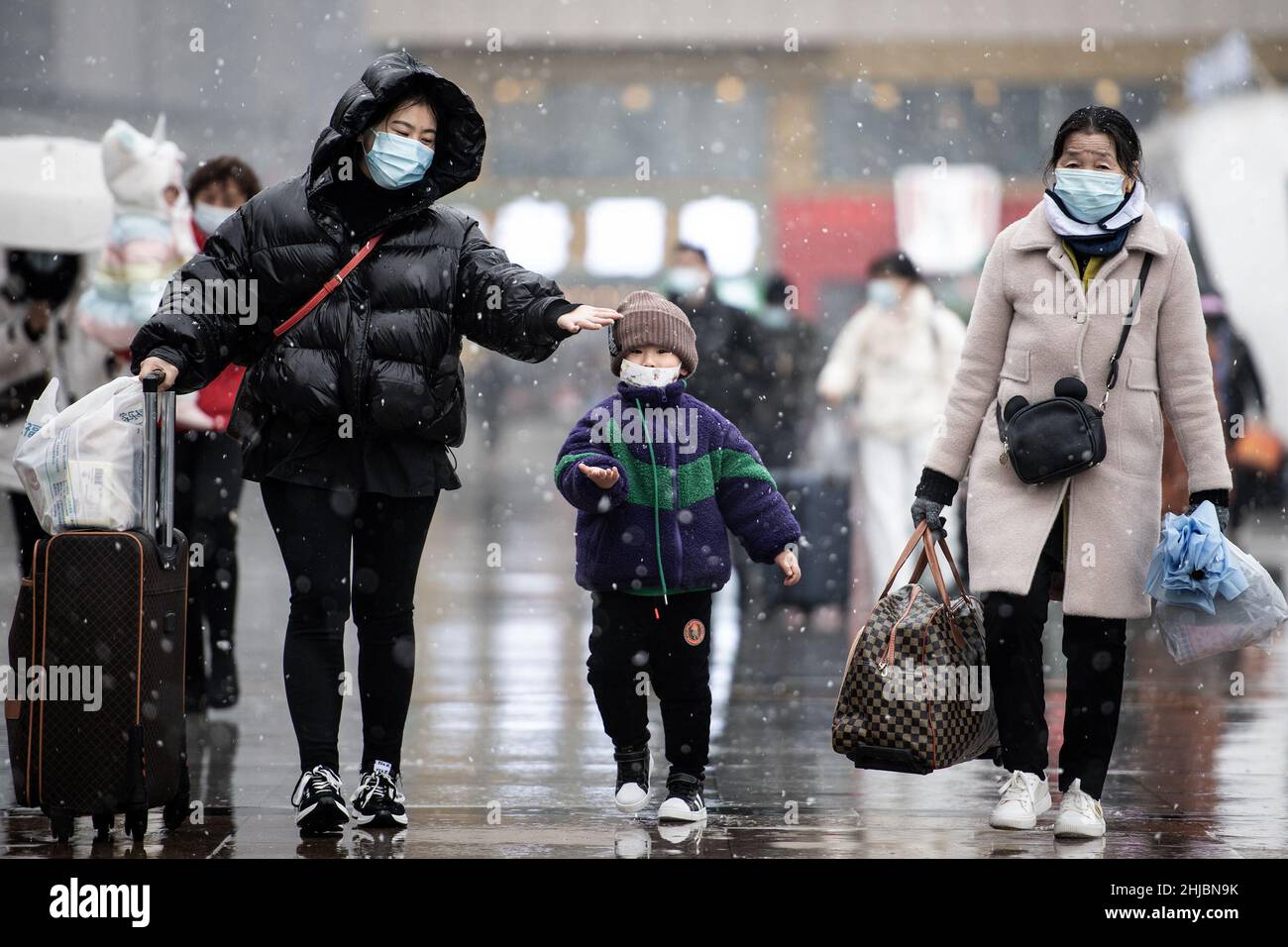 Wuhan, Cina. 28th Jan 2022. Una donna con il suo bambino a piedi nella nevicata alla stazione ferroviaria di Hankou a Wuhan.Un totale di 2,8 miliardi di viaggi passeggeri sono attesi durante i 40 giorni 'Chunyun, ' o corsa di viaggio Festival di primavera, che ha iniziato dal 17 gennaio di quest'anno. Milioni di cinesi si recheranno a casa per visitare le famiglie in massa durante il periodo di festa di Primavera che inizia con il Capodanno lunare il 1 febbraio. (Foto di Ren Yong/SOPA Images/Sipa USA) Credit: Sipa USA/Alamy Live News Foto Stock