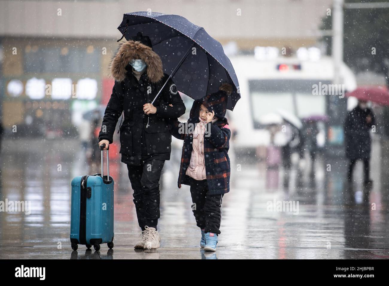 Wuhan, Cina. 28th Jan 2022. Una donna con il suo bambino a piedi nella nevicata alla stazione ferroviaria di Hankou a Wuhan.Un totale di 2,8 miliardi di viaggi passeggeri sono attesi durante i 40 giorni 'Chunyun, ' o corsa di viaggio Festival di primavera, che ha iniziato dal 17 gennaio di quest'anno. Milioni di cinesi si recheranno a casa per visitare le famiglie in massa durante il periodo di festa di Primavera che inizia con il Capodanno lunare il 1 febbraio. Credit: SOPA Images Limited/Alamy Live News Foto Stock