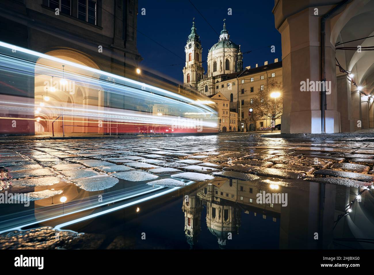 Leggero sentiero di tram che passa tra edifici storici. Riflessione in pozzanghere su strada bagnata. Città minore di Praga, Repubblica Ceca. Foto Stock