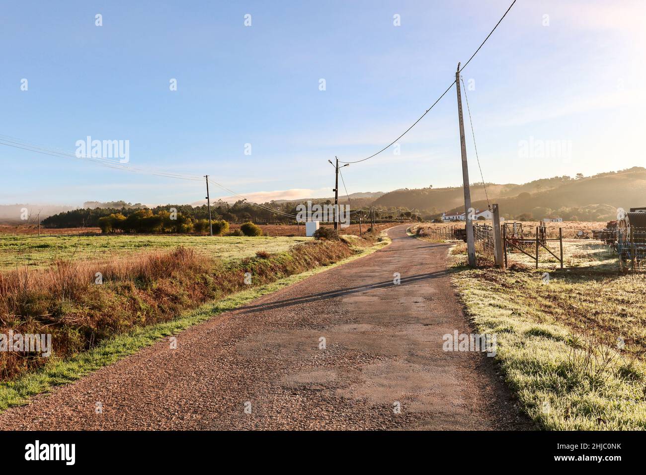 Vista sul paesaggio tipico dell'Alentejo con villaggio portoghese al mattino nebbia un sole che sorge sul sentiero escursionistico Rota Vicentina vicino a Carrascalinho, Aljezur Foto Stock