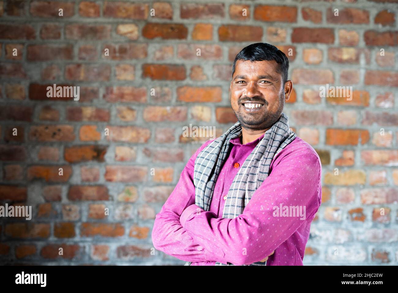 Sorridente lavoratore di costruzione sicuro si gira guardando la macchina fotografica sul posto di lavoro - concetto di lavoro manuale e felicità Foto Stock