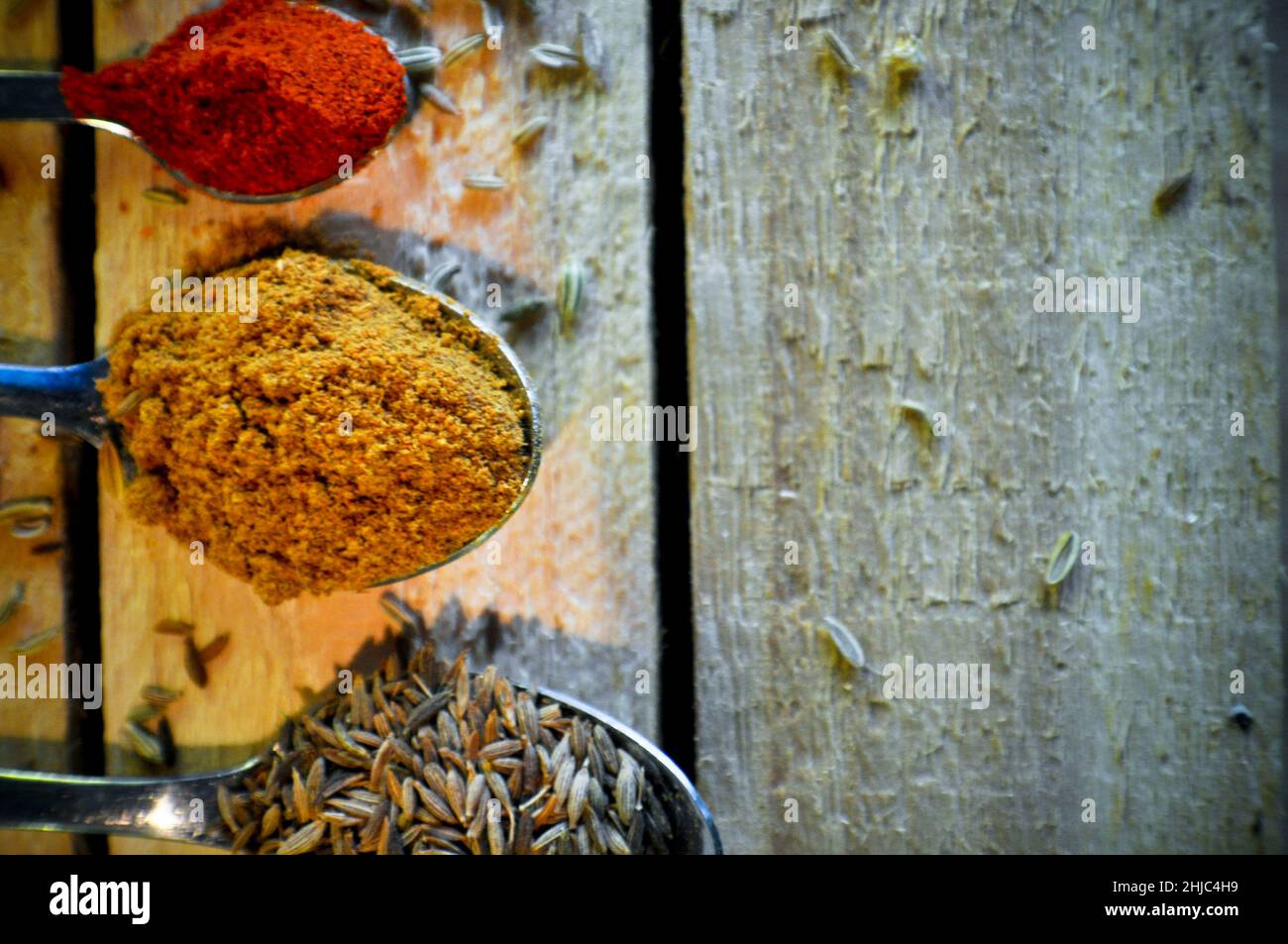 Una varietà di cucchiai con spezie diverse su di essi, adagiato su un rustico sfondo di legno. Lo spazio di copia è stato lasciato Foto Stock