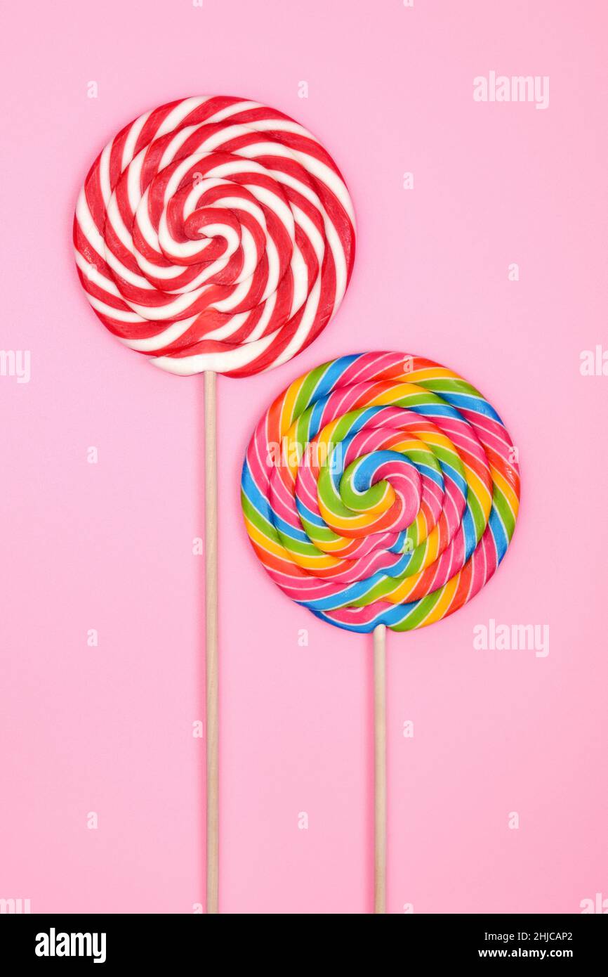 Due lollipops rotondi colorati sui bastoni, su un morbido sfondo rosa. La composizione verticale. Foto Stock