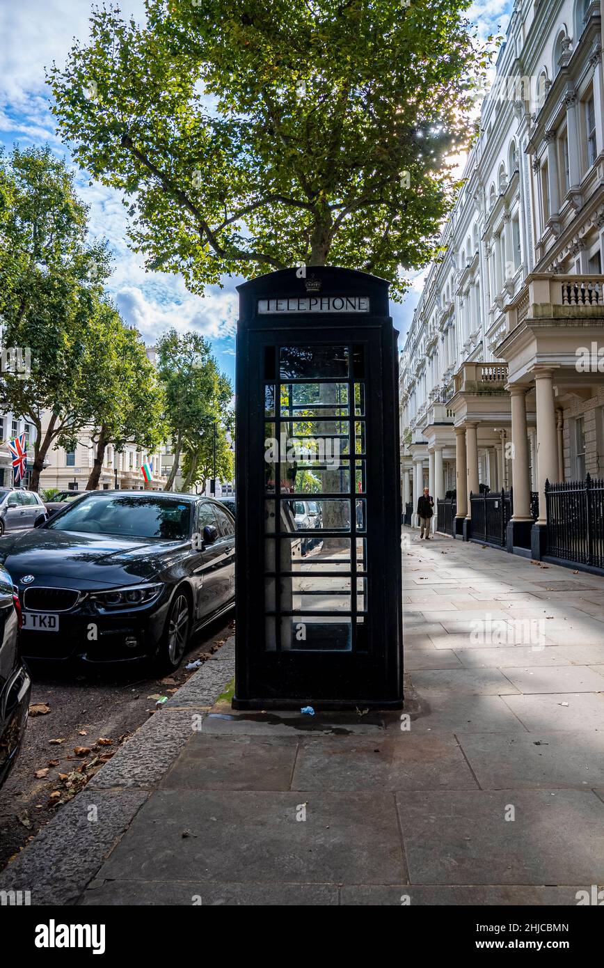 Cabina telefonica sulla passerella pedonale accanto alle auto parcheggiate sulla strada Foto Stock