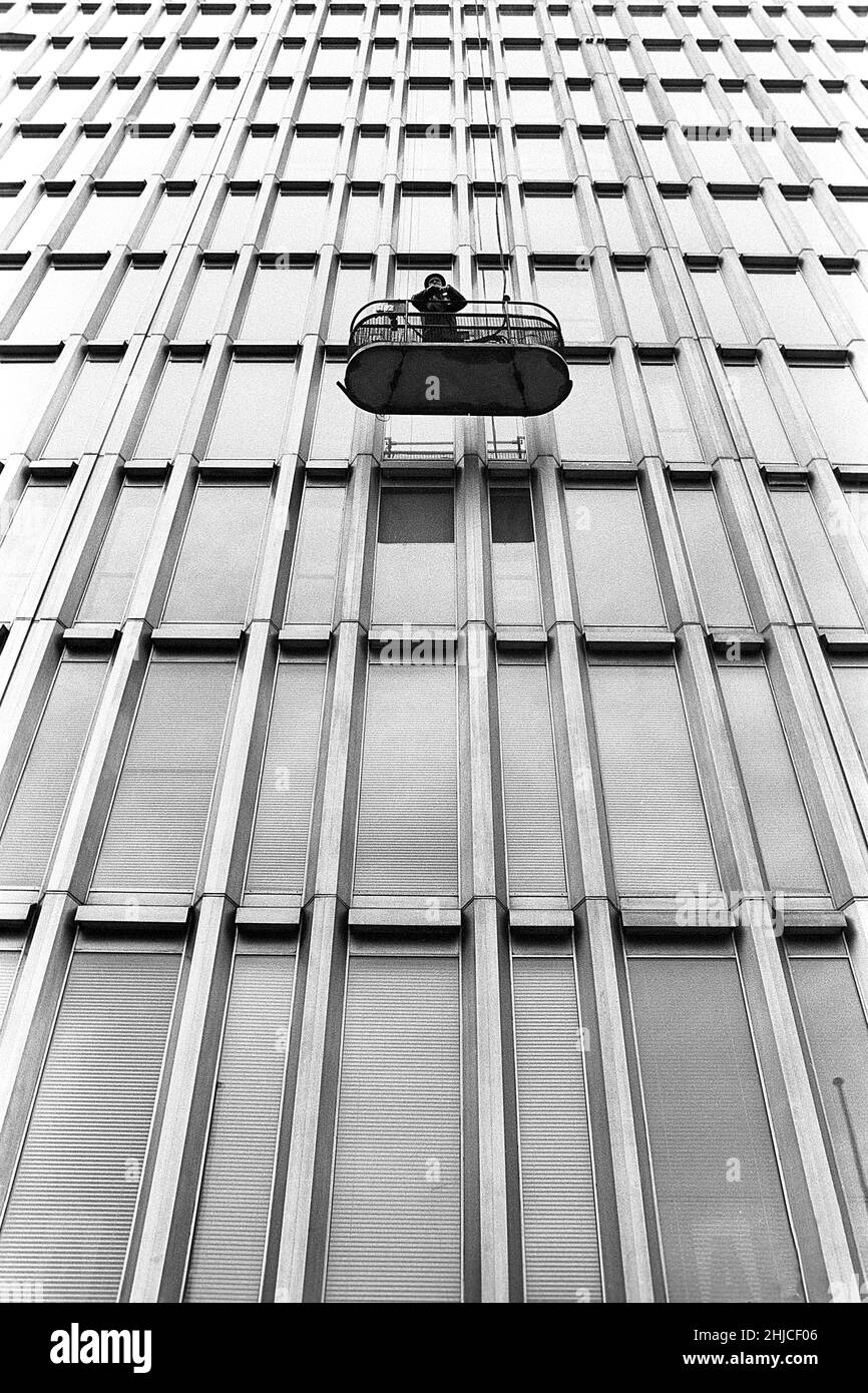 Stoccolma nel 1960s. Un uomo in un cesto mobile è visto fuori dalla fascia di uno degli edifici alti nel centro di Stoccolma, il cosiddetto Hötorgsskraporna. Il cesto è più o meno un ascensore che va su e giù come avete scelto e funziona come manutenzione generale e la pulizia delle finestre sono stati eseguiti da esso. Svezia 1964 Kristoffersson Ref 3-53 Foto Stock