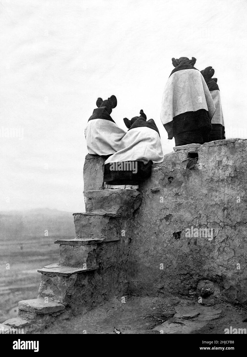 Edward S Curtis Fotografia intitolata Watching the danzers - quattro ragazze Hopi su un tetto guardare una danza pueblo sotto - Walpi Pueblo, Arizona 1906 Foto Stock
