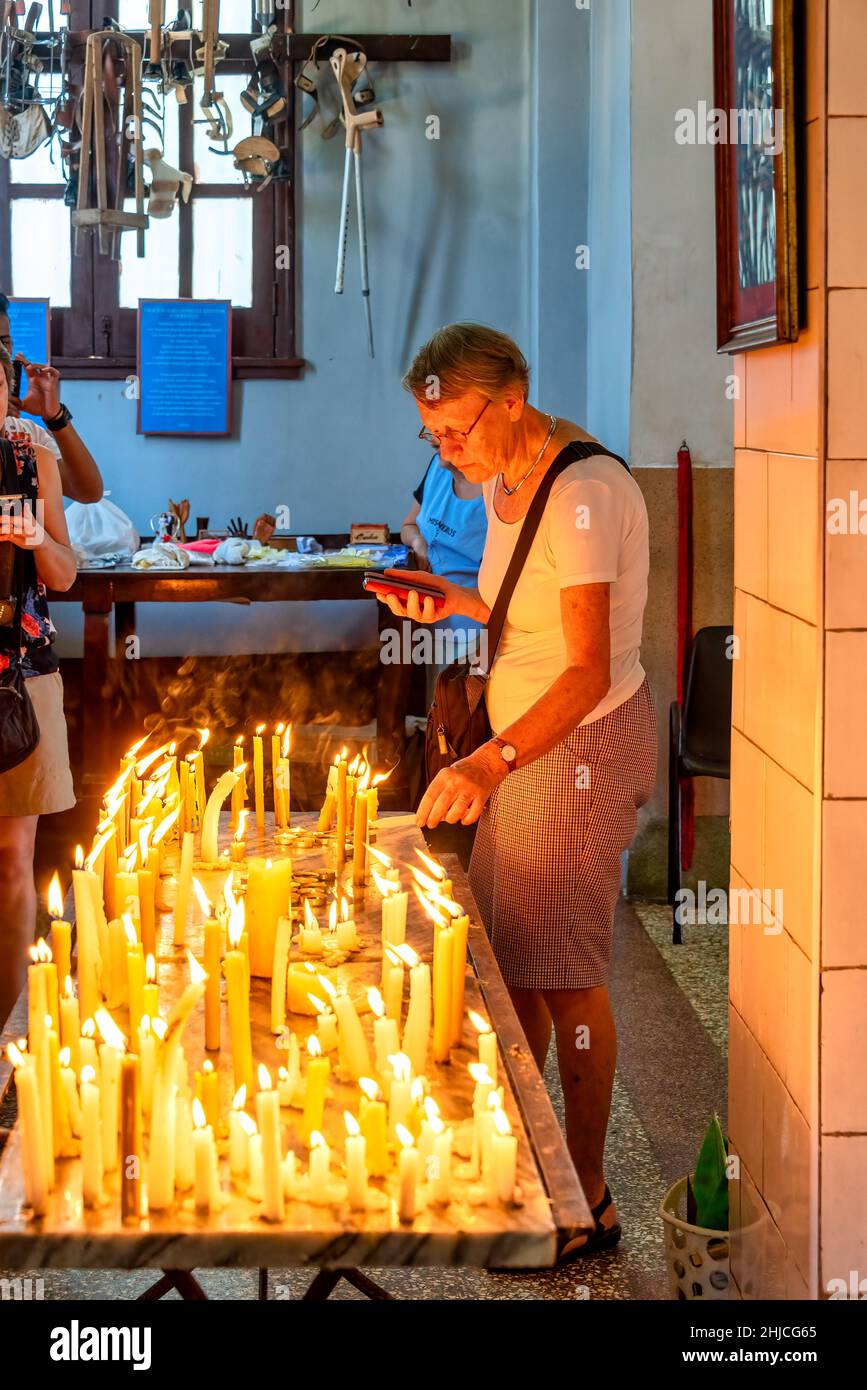 I turisti stranieri fulminano una candela nella chiesa della basilica di nostra Signora della Carità di El Cobre. Il tempio cattolico romano è un luogo di maggiore peregrinazione nel Th Foto Stock