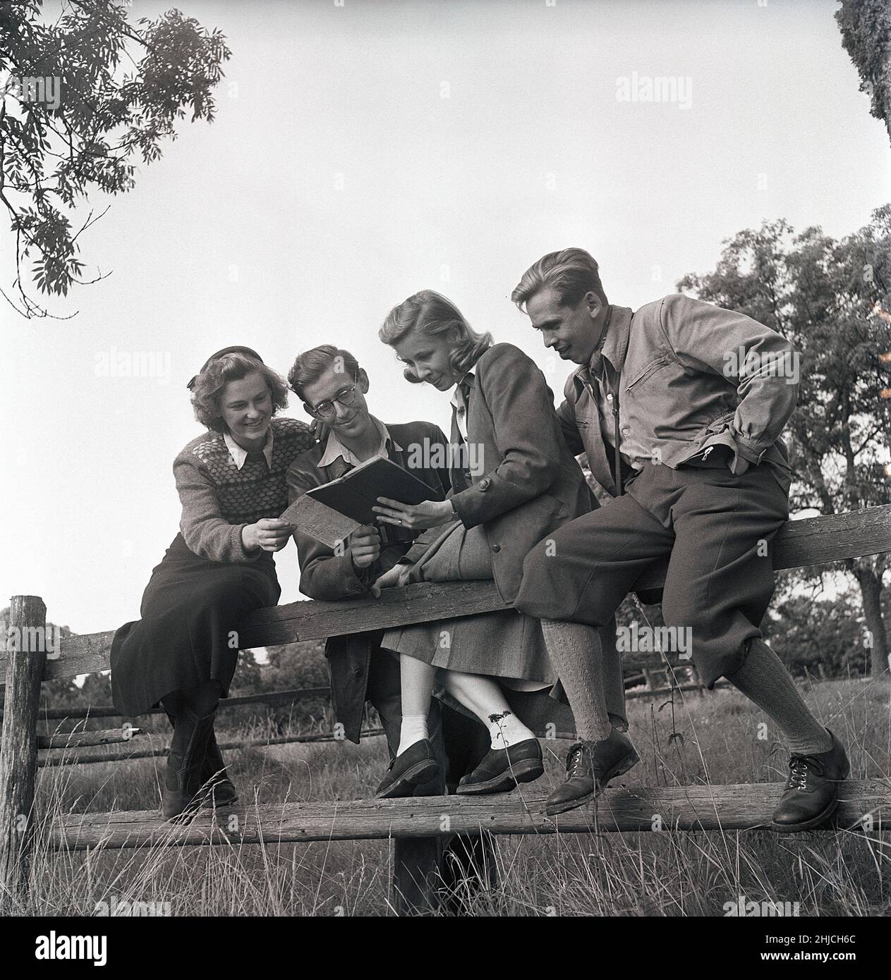 1940s vita all'aperto. Un gruppo di giovani è fuori dalla natura ed è interessato a piante e fiori. Indossano il tipico 1940s tipo di abbigliamento da esterno di carattere sportivo che è pratico e durevole. Studiano il libro che hanno preso con loro che il più probabilmente è circa qualche cosa relativa al loro giorno in natura. Svezia 1949. Foto Kristoffersson Rif AT1-7 Foto Stock
