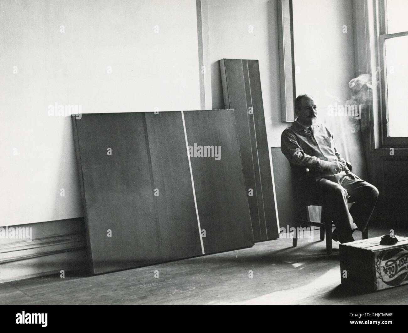 L'espressionista astratto americano e il pittore minimalista Barnet Newman (1905-1970) con alcuni dei suoi lavori a New York City, 1952. Foto Stock