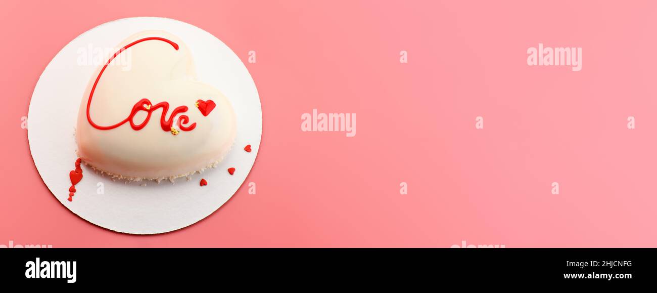 Una torta a forma di cuore. Torta di mousse a forma di cuore con l'iscrizione amore su sfondo rosa. Banner di San Valentino per panetteria Foto Stock