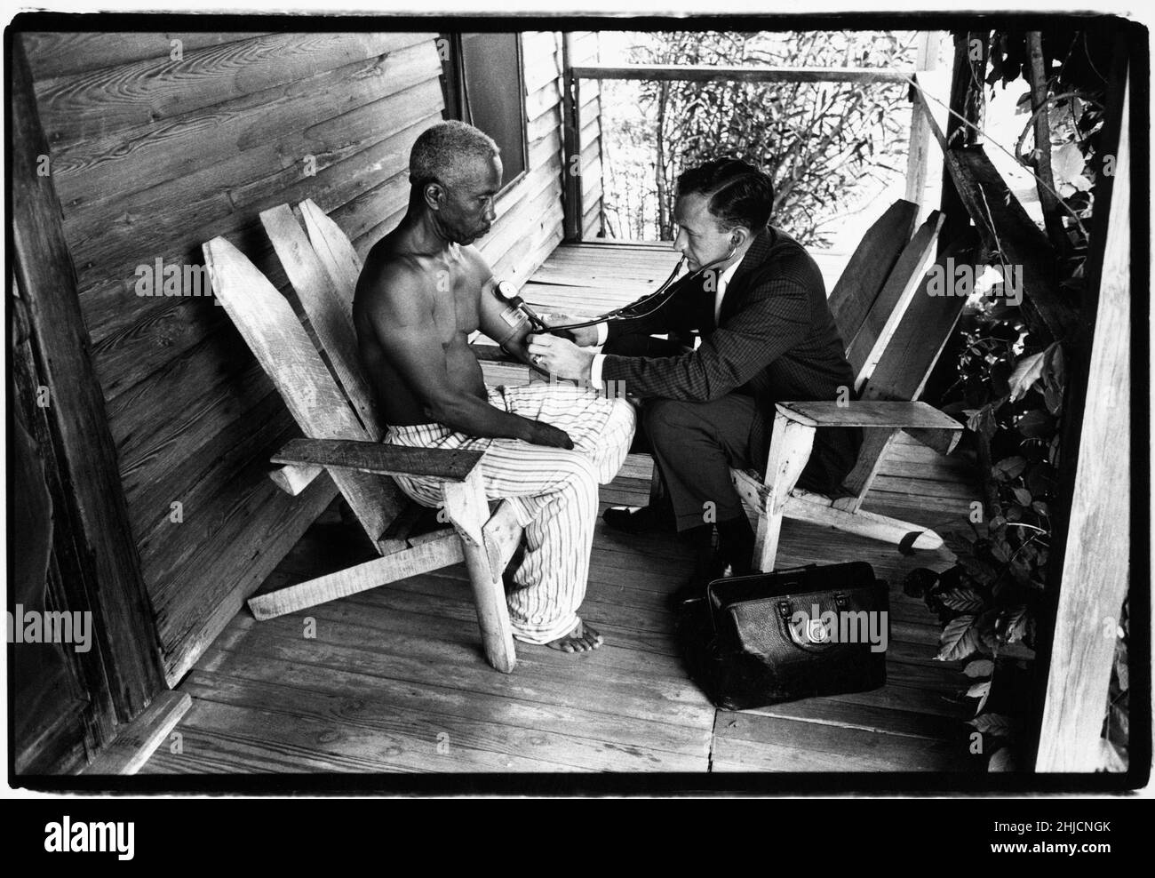 Il Dr. Lloyd McCaskill di Maxton, NC tratta un paziente sul portico della sua casa. Questo era tipico delle visite a casa perché c'era spesso più luce all'aperto. Foto Stock