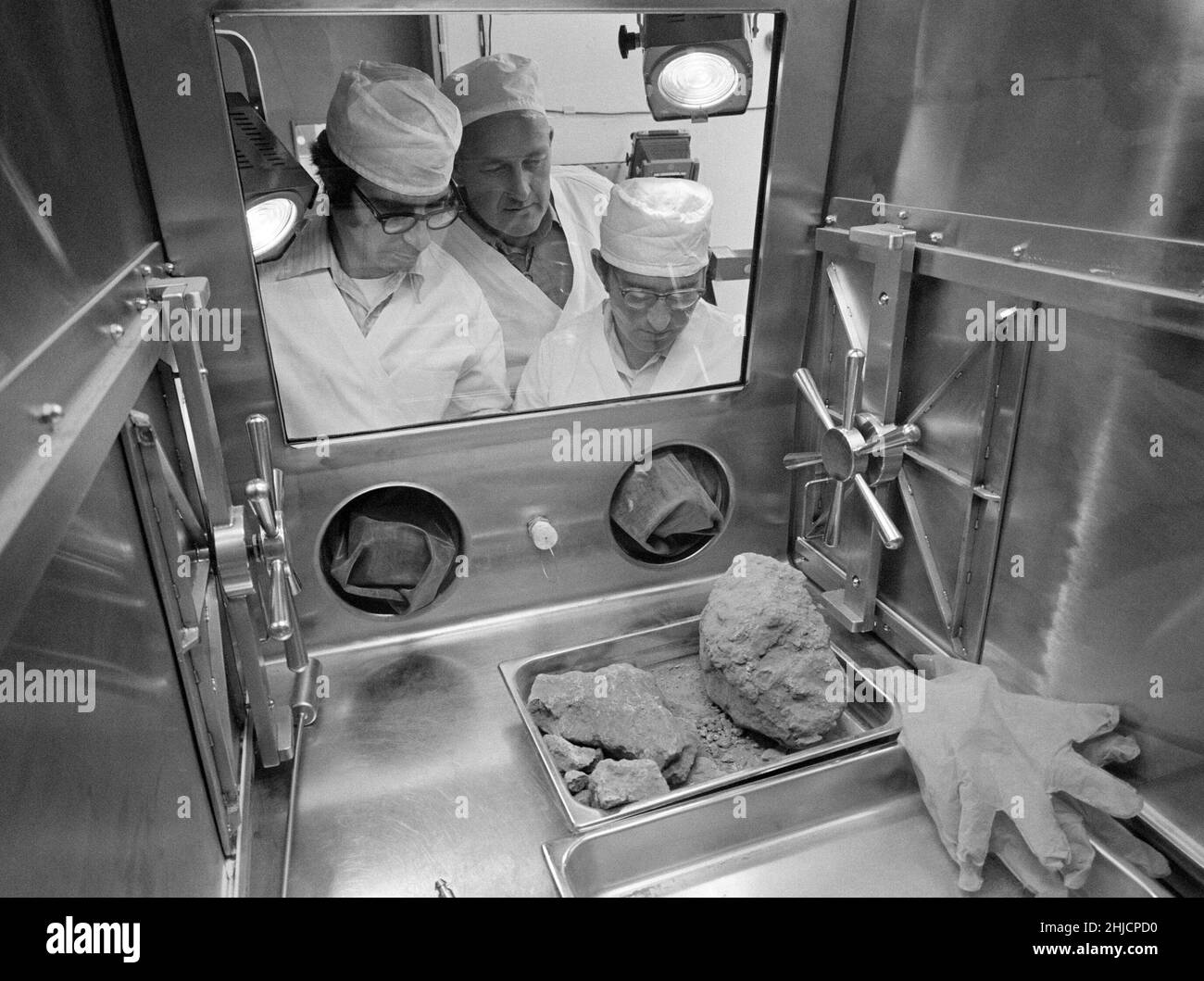 Nel Lunar Receiving Laboratory presso la NASA‚Äôs presidiato Spacecraft Center, i geologi Don Morrison (a sinistra) e Fred Horz fiancheggiano la University of Texas geologo/professore William (Bill) Muehlberger mentre i tre guardano una roccia riportata dalla luna dagli astronauti Apollo 16. Il campione lunare 61016, meglio noto come ‚ÄòBig Muley‚Äô, è un grande campione di breccia, la più grande roccia lunare restituita da qualsiasi equipaggio Apollo, che è stato chiamato da Muehlberger, il leader del team di geologia sul campo Apollo 16. Maggio 19, 1972. Foto Stock