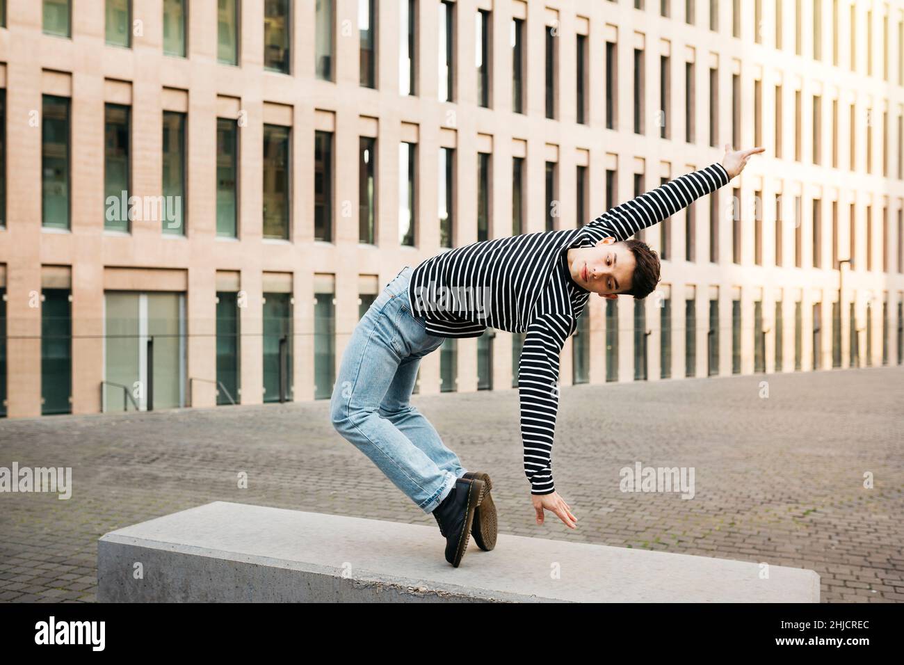 Giovane uomo che fa danza acrobatica su una panchina di strada Foto Stock