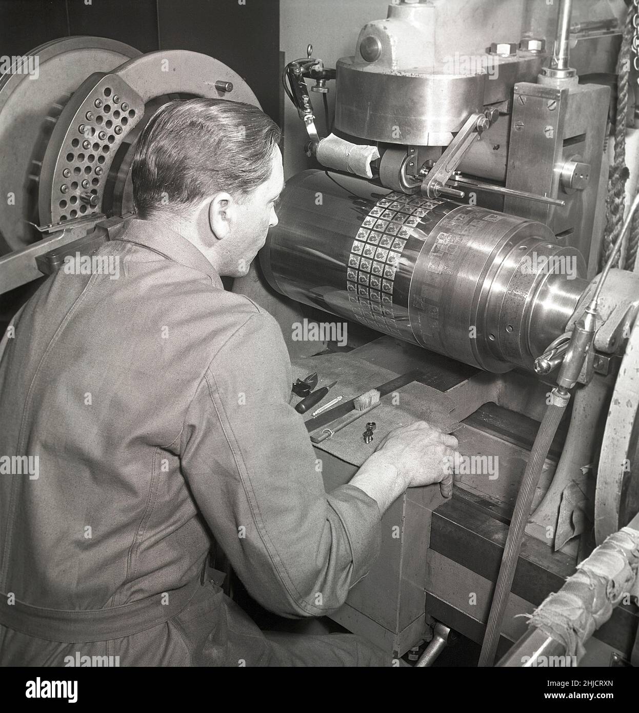 Produzione di francobolli nel 1950s. Uomo con la macchina che realizza il cilindro di stampa che in seguito verrà utilizzato per stampare i timbri dei nuovi timbri Gustaf Adolf. Un totale di 340 incisioni a stampo sono montate sul cilindro in negativo. Svezia 1951 Kristoffersson Ref bc45-11 Foto Stock