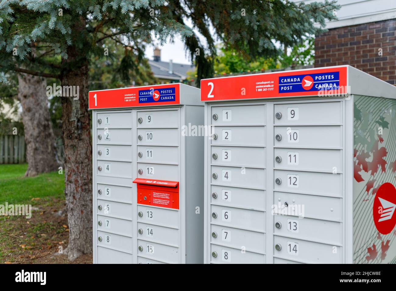 Ottawa, Canada - Ottobre, 2021: Canada posta caselle di posta set nella comunità di quartiere vicino case con segno rosso in inglese e francese Foto Stock