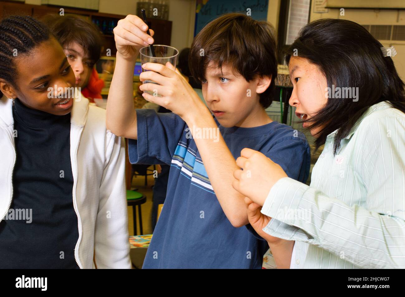 Istruzione elementare o scuola media di grado 6 classe scientifica estrazione del DNA ragazzo e due ragazze che lavorano all'esperimento Foto Stock