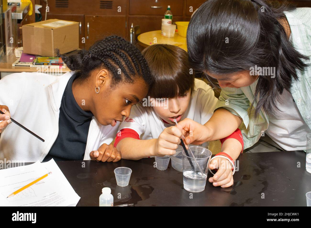 Istruzione elementare o scuola media di grado 6 classe scientifica estrazione del DNA, ragazzo e due ragazze che lavorano a un esperimento Foto Stock