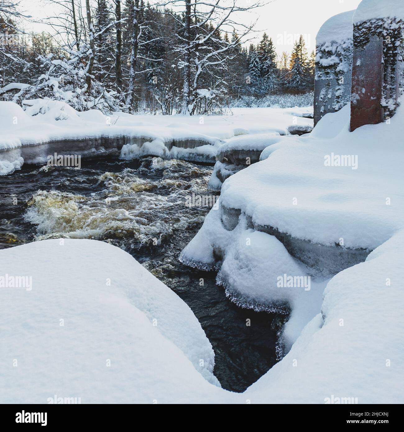 Flusso d'acqua di un piccolo fiume di foresta innevato, frammenti di ghiaccio da vicino. Esposizione prolungata. Concetto di riscaldamento globale, ecologia, conservazione ambientale, g Foto Stock