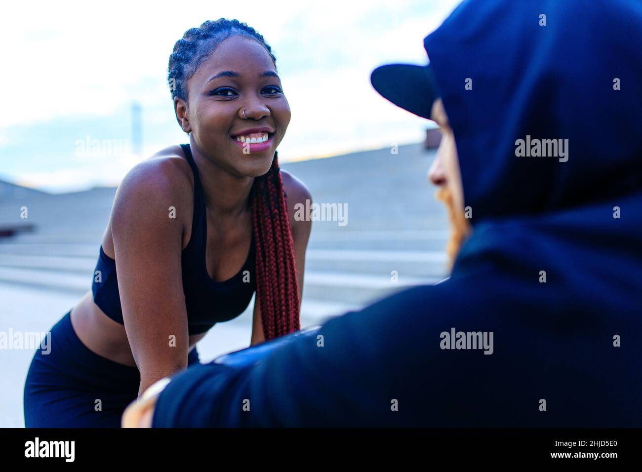 spagna donna con afro pigtail crossfit trainer motivando il suo ragazzo per la mattina di correre all'aperto in sity Foto Stock