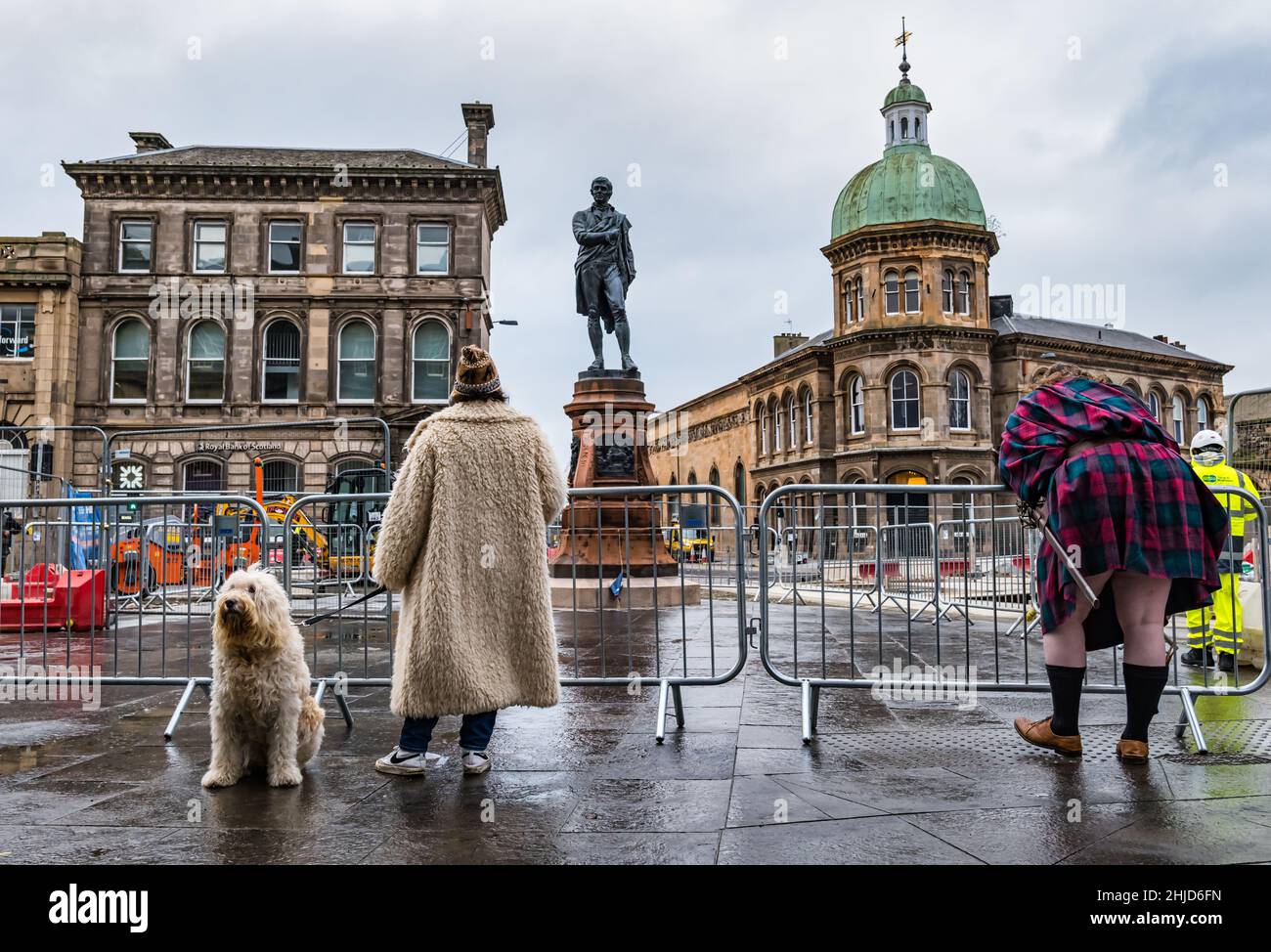 Restaurata la statua di Robert Burns reintegro dopo il lavoro di costruzione di tram con donna e cane e uomo che indossano kilt, Leith, Edimburgo, Scozia Foto Stock