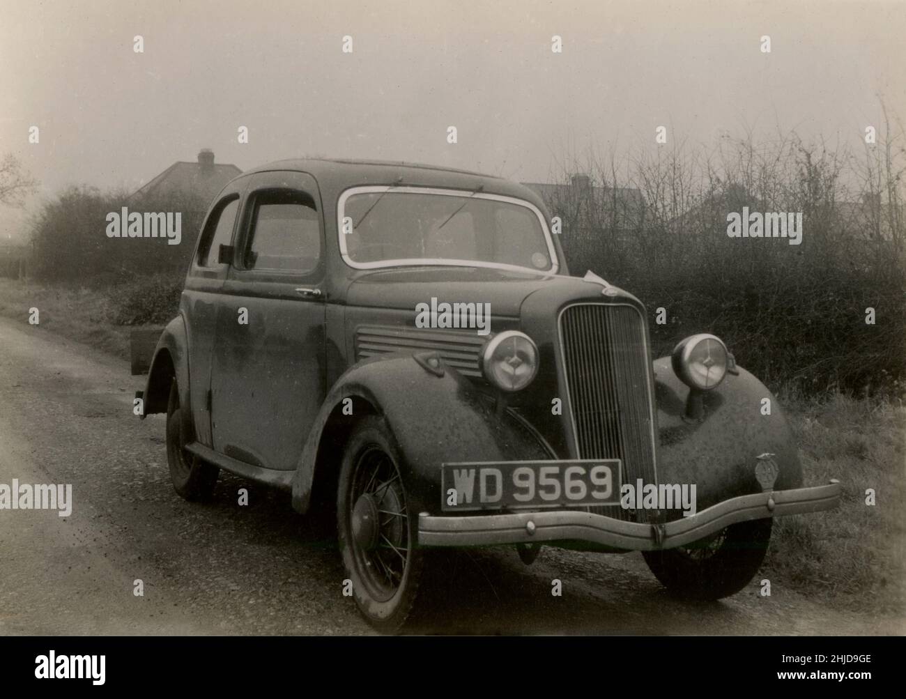 1940s, storico, al mattino presto e un fangoso Ford Model C Ten, parcheggiato su una corsia da un hedgerow, Essex, Inghilterra, Regno Unito. La vettura è stata fabbricata in Gran Bretagna tra il 1934 e il 1937, con i 'dieci' relativi alla sua potenza fiscale britannica del 10. Foto Stock