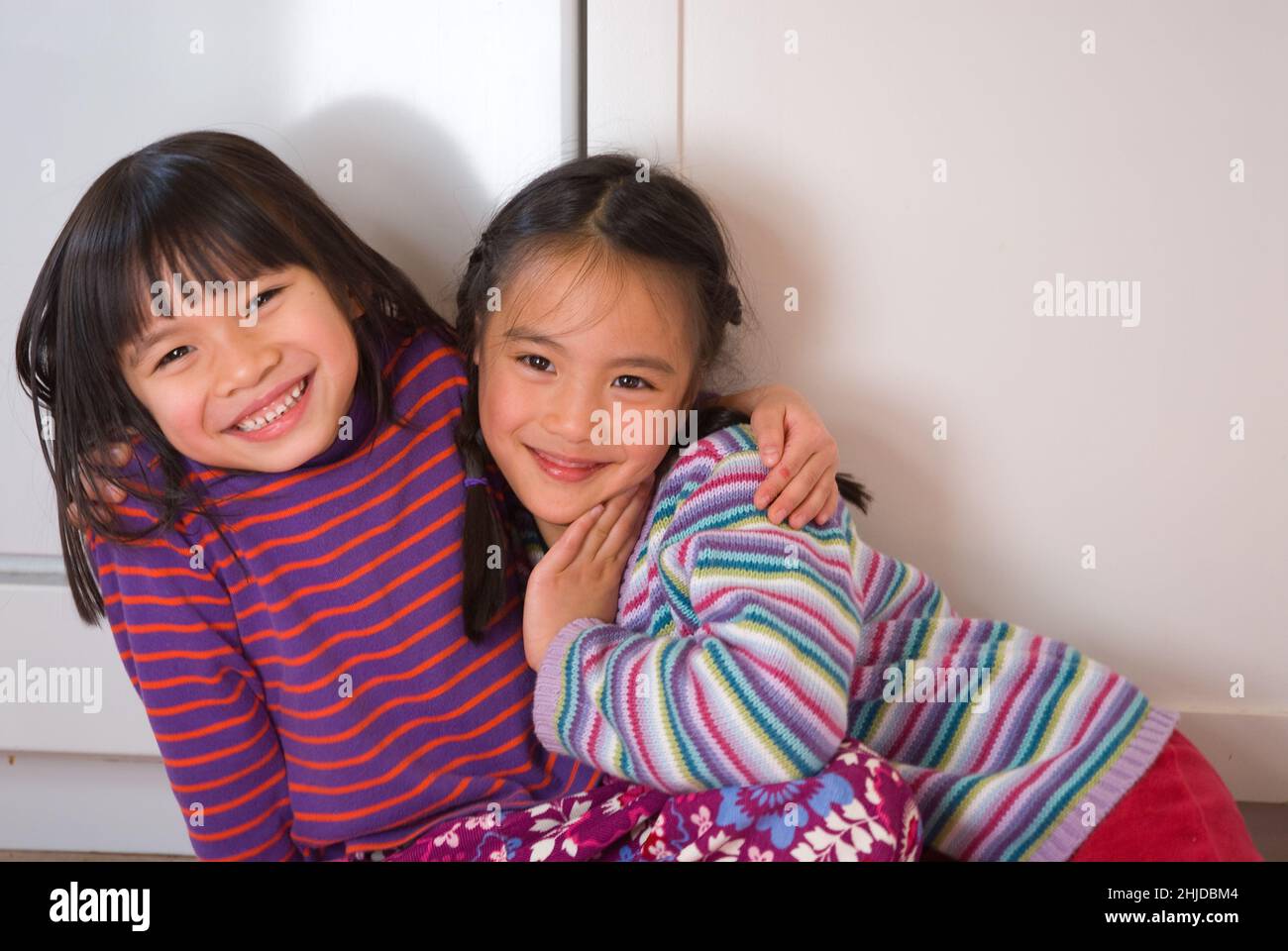 Due ragazze di cinque anni che abbraccia, amici fin dall'infanzia, sorridendo, guardando la macchina fotografica Foto Stock