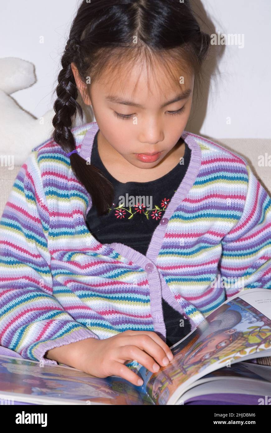 ragazza di 5 anni seduta e lettura libro di immagini Foto Stock