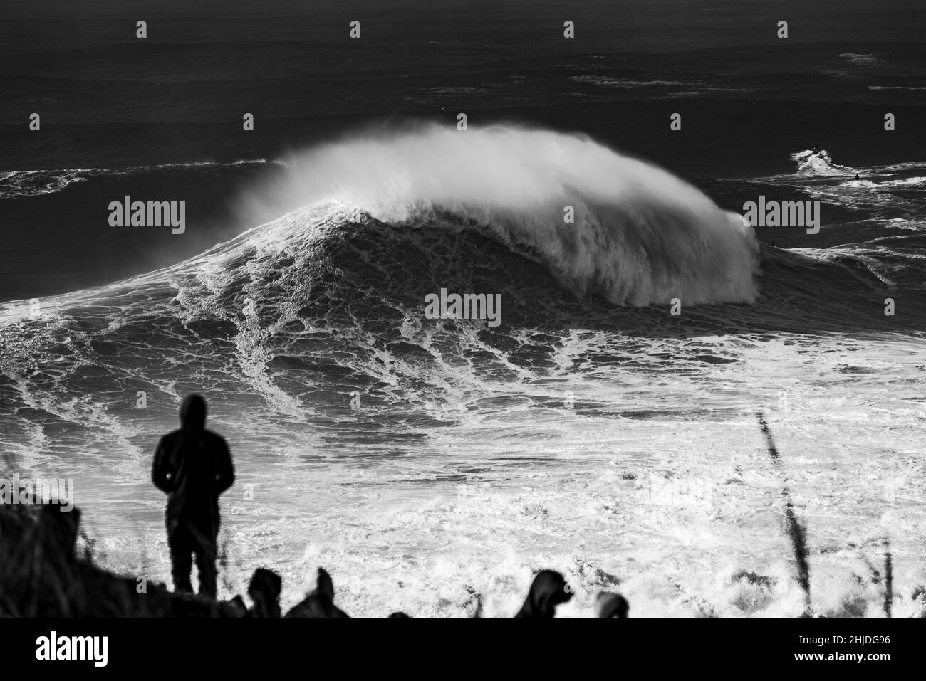 Gruppo di persone che guardano e fotografano grandi onde tempestose sul mare vicino a Nazare, Portogallo Foto Stock