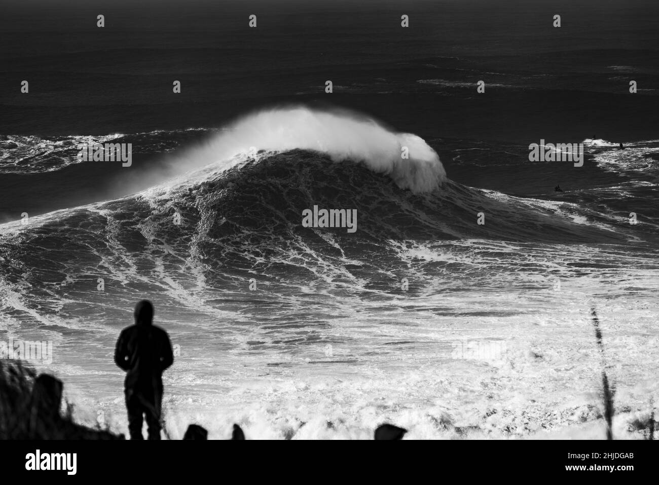 Maschi guardando e foto grandi onde tempestose sul mare vicino Nazare, Portogallo Foto Stock