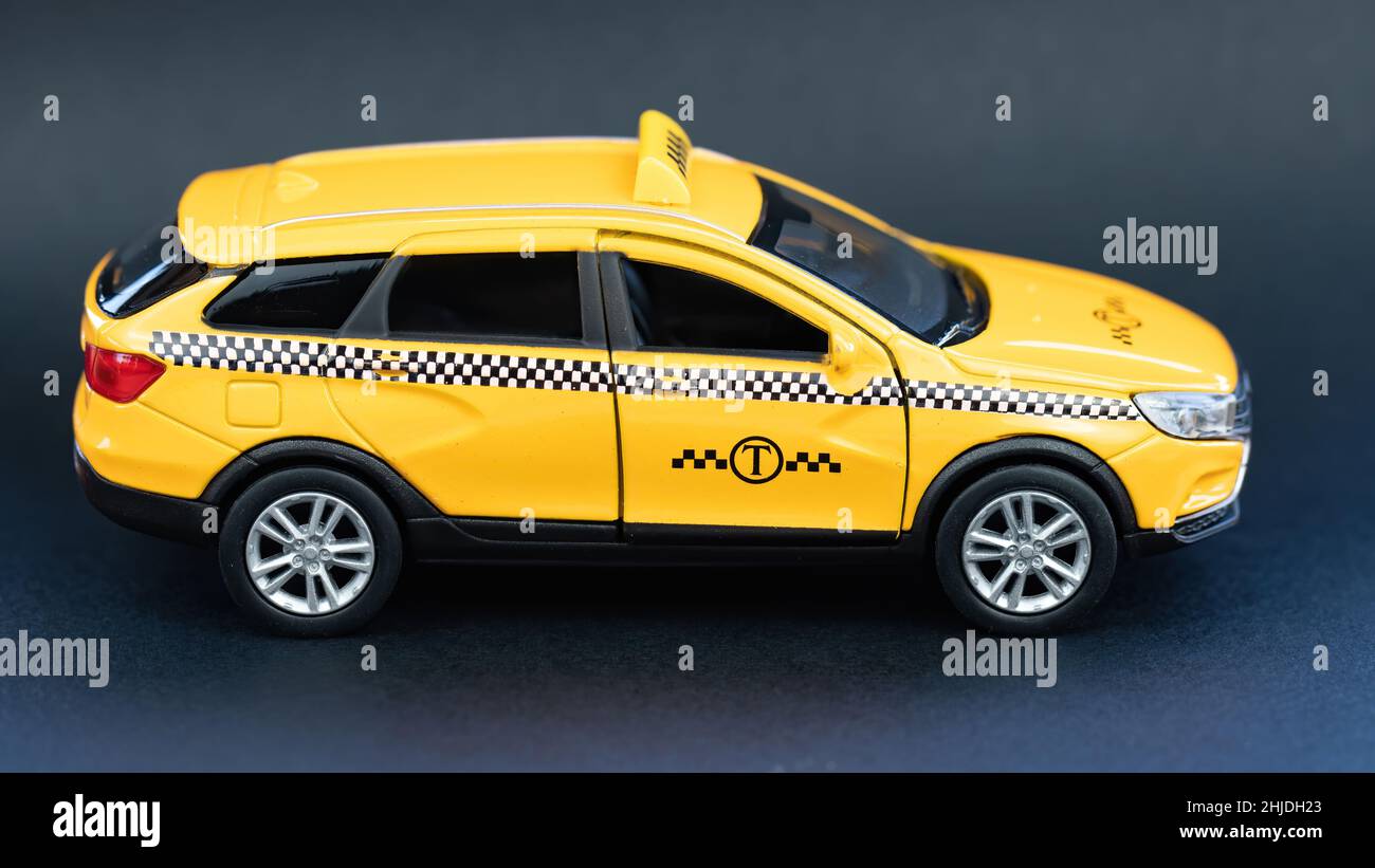 Vista laterale taxi giallo su sfondo nero macro fotografia. Banner pubblicitario del servizio taxi. Concetto di noleggio auto. Come spostarsi in città in taxi. Foto Stock
