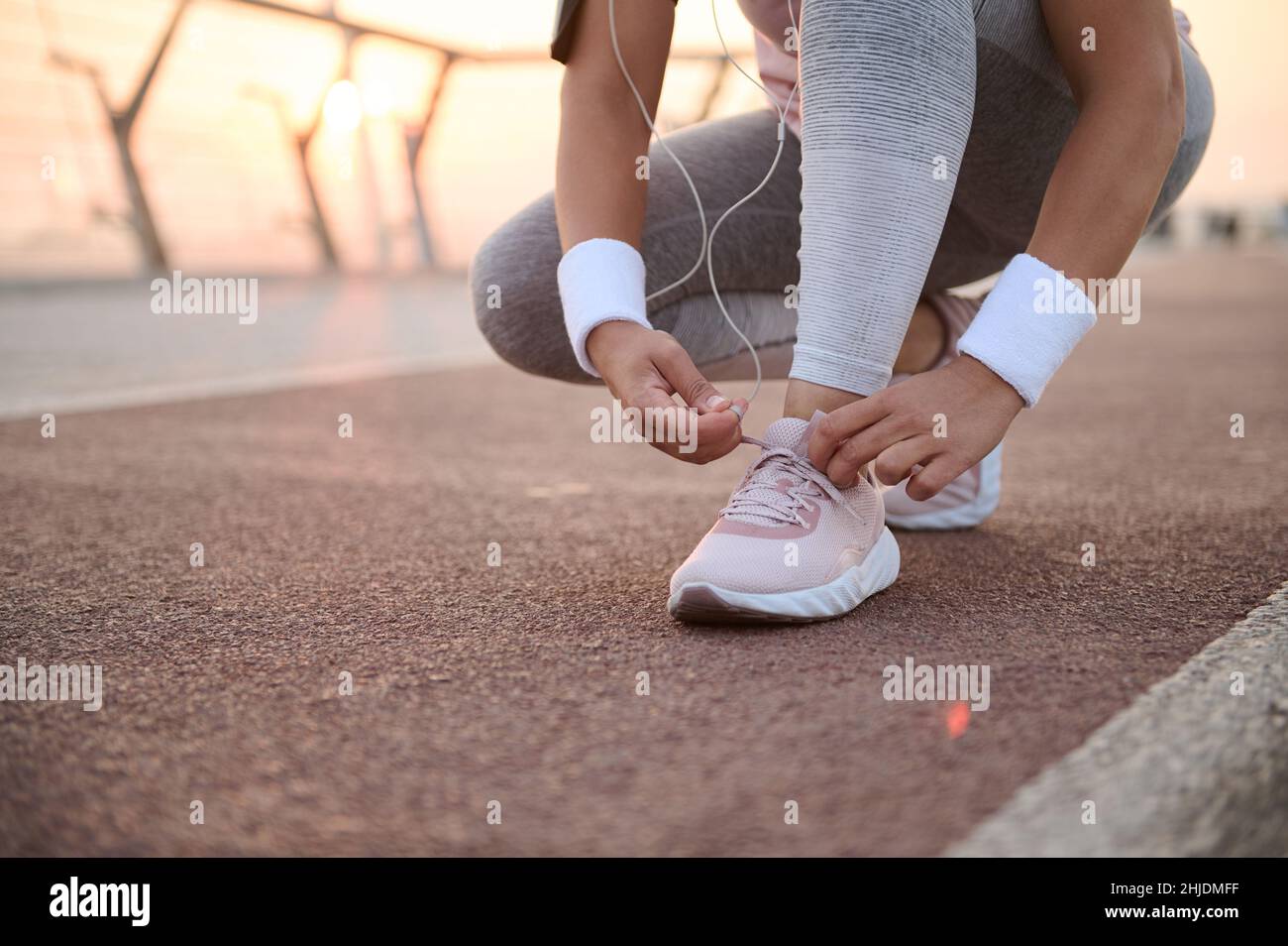 Immagine ritagliata di una donna fitness irriconoscibile che lega le scarpe alle sneakers e si prepara per la corsa mattutina e l'allenamento sportivo all'aperto su un ci Foto Stock