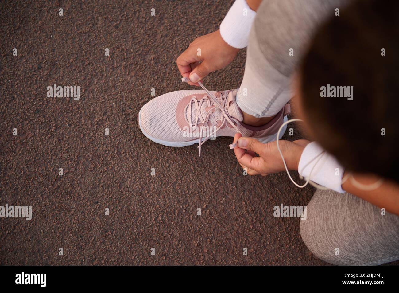 Vista dall'alto di un atleta che lega i lacci di sneaker accoccolati su un tapis roulant mentre si prepara per una corsa all'aperto. Sport, stile di vita attivo sano, salute e. Foto Stock