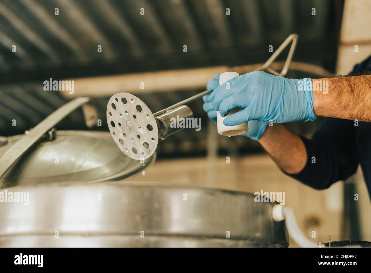 le mani di un uomo raccolgono un campione di latte per l'analisi Foto Stock