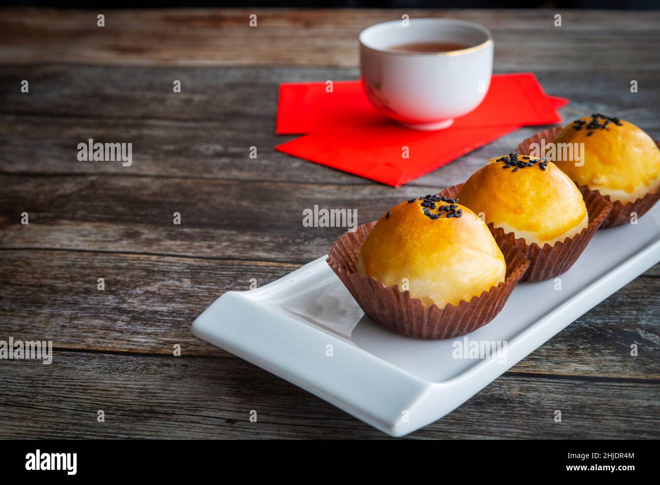 Dolci tradizionali cinesi di capodanno cotti con pasta soffice e ripieni di tuorlo d'uovo salato e pasta dolce. Denaro fortunato cinese pacchetti rossi e tè Foto Stock