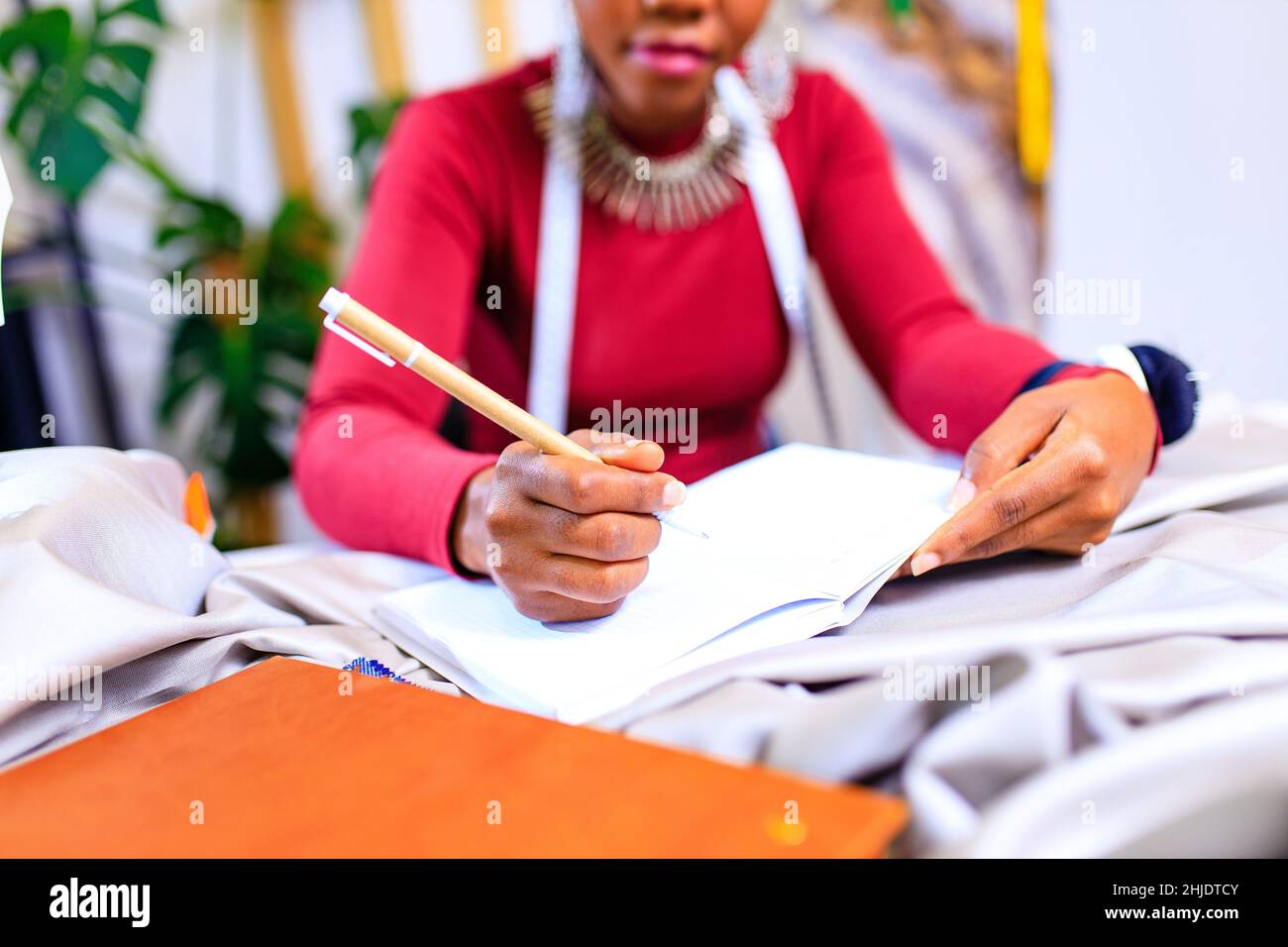 tanzanian donna con serpente stampa turban oltre sentire lavorare in casa di moda Foto Stock