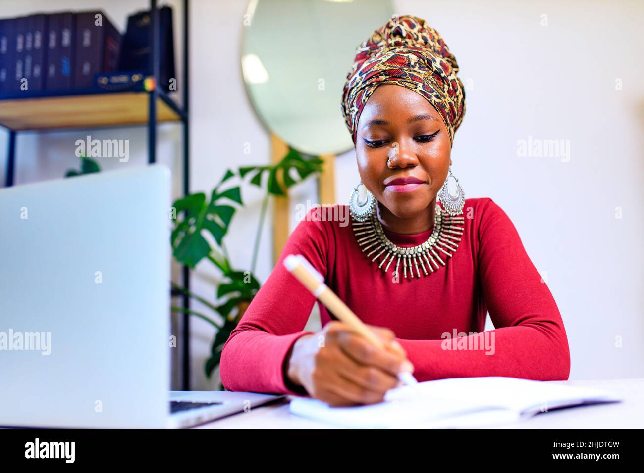 Immagine di una donna afroamericana con turbante sopra la testa utilizzando un computer portatile in ufficio Foto Stock