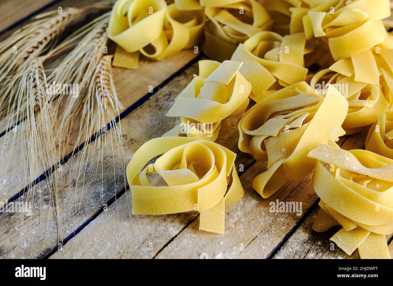 vermicelli nidi e spighe di grano su una superficie di legno Foto Stock