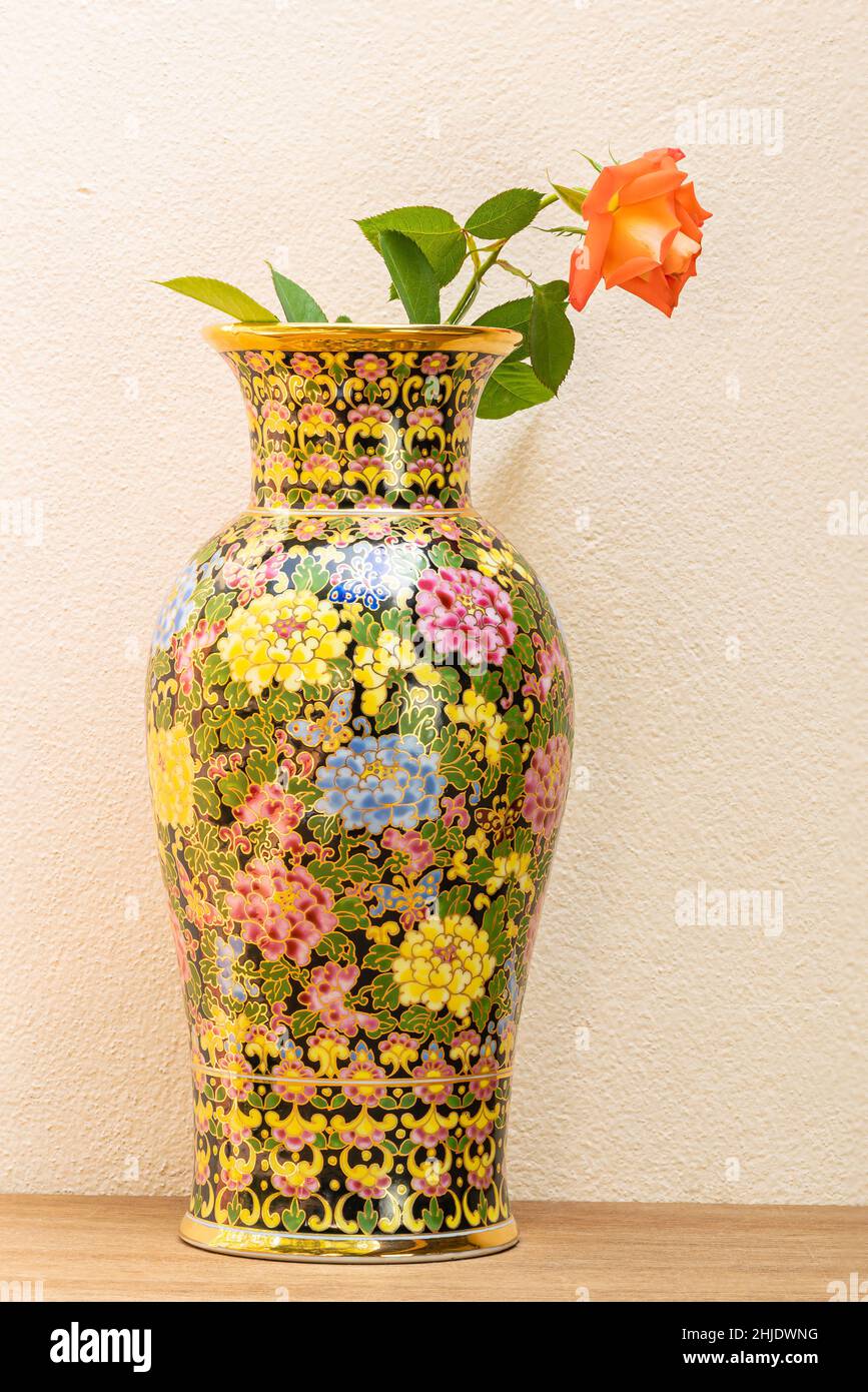 Vaso Benjarong con rosa rossa su tavola di legno. Bel prodotto souvenir della Thailandia, Benjarong Vase. Benjarong è un design in porcellana thailandese in cinque colori Foto Stock
