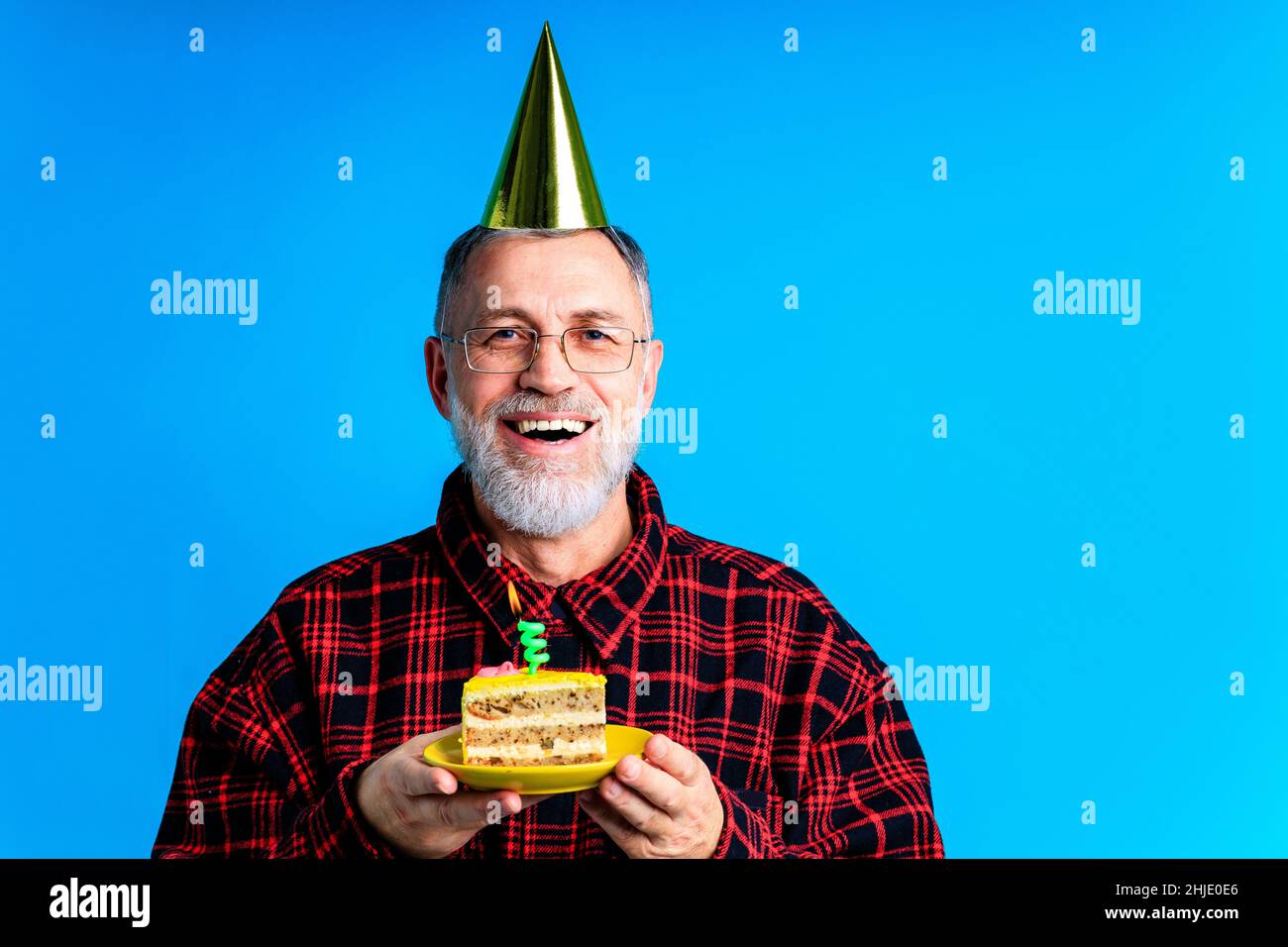 uomo che indossa cappello di compleanno con torta isolato su sfondo di colore blu chiaro, ritratto studio Foto Stock