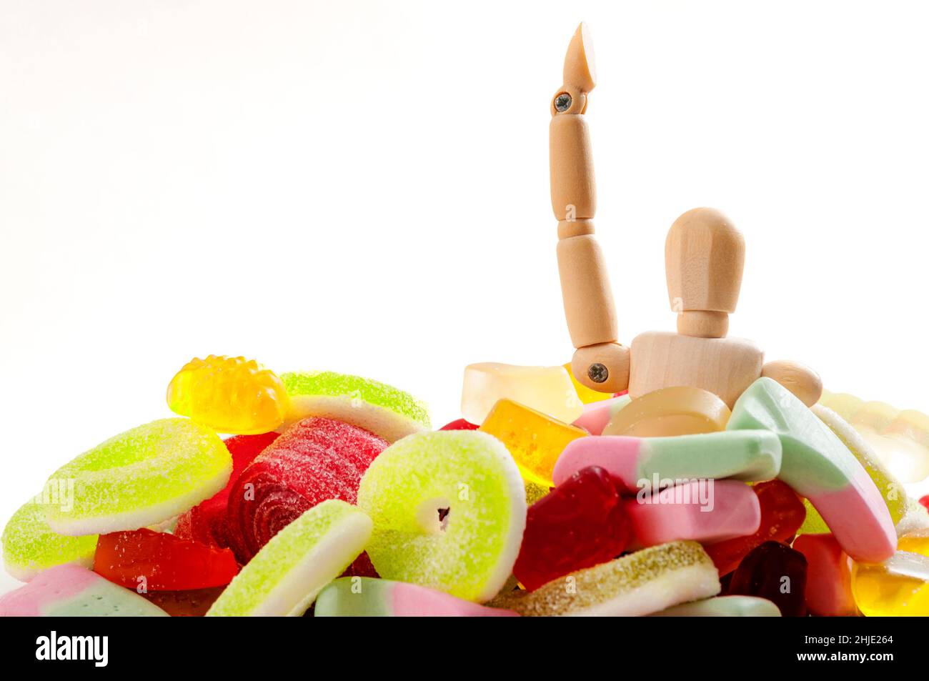 Abitudini alimentari malsane, il 14 novembre è il giorno della consapevolezza del diabete e cattivo concetto di dieta con un pupazzo annegato in dolci zuccherati e cibo spazzatura isolato sopra Foto Stock