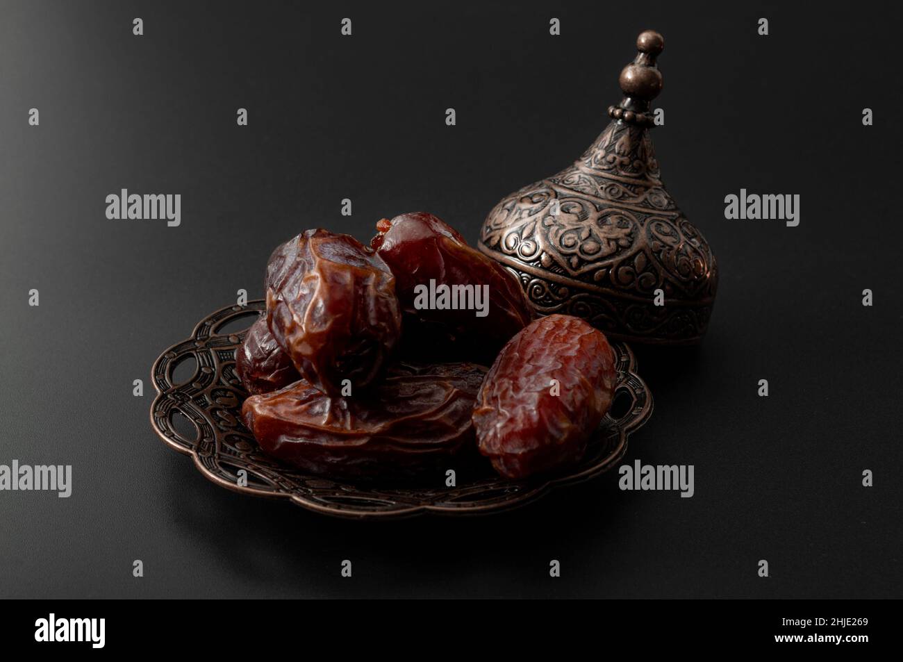 Dolci Ramadan e frutta secca medio orientale concetto con primo piano su servire di datteri secchi su piastra di metallo splendidamente ornata isolato su nero backgr Foto Stock