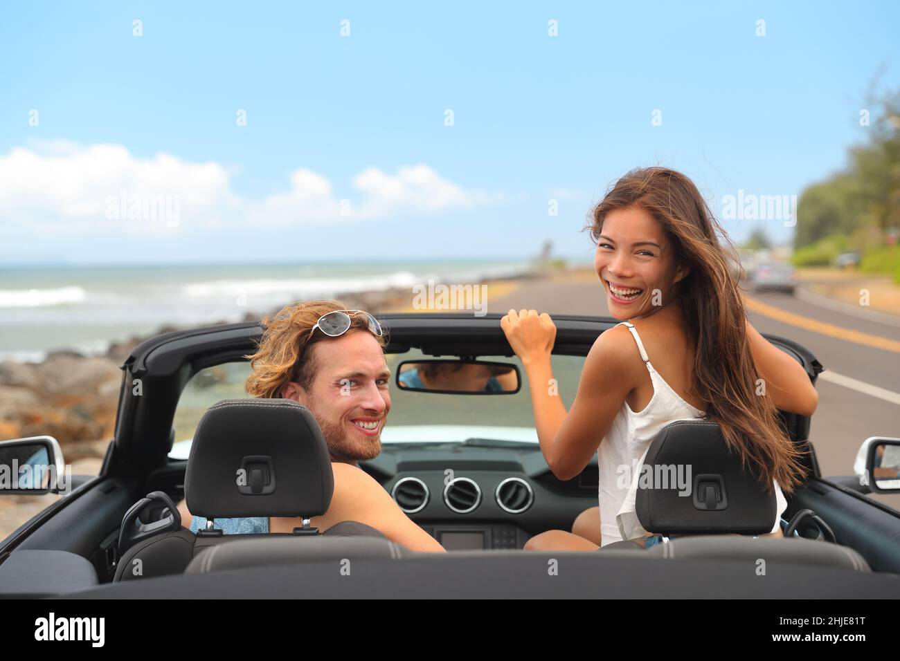 Road viaggio auto noleggio viaggio felice gente giovani turisti coppia sorridente a macchina fotografica guida in vacanza estate viaggio. Donna asiatica, uomo caucasico Foto Stock