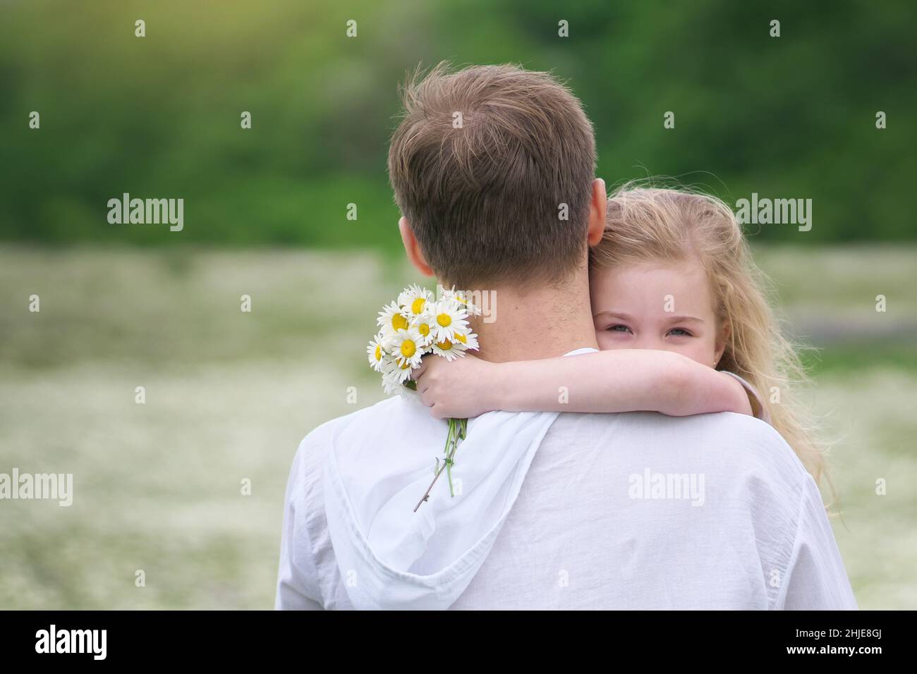 Padre e figlia nel grande prato di montagna camomilla. Scena emozionale, d'amore e di cura. Foto Stock