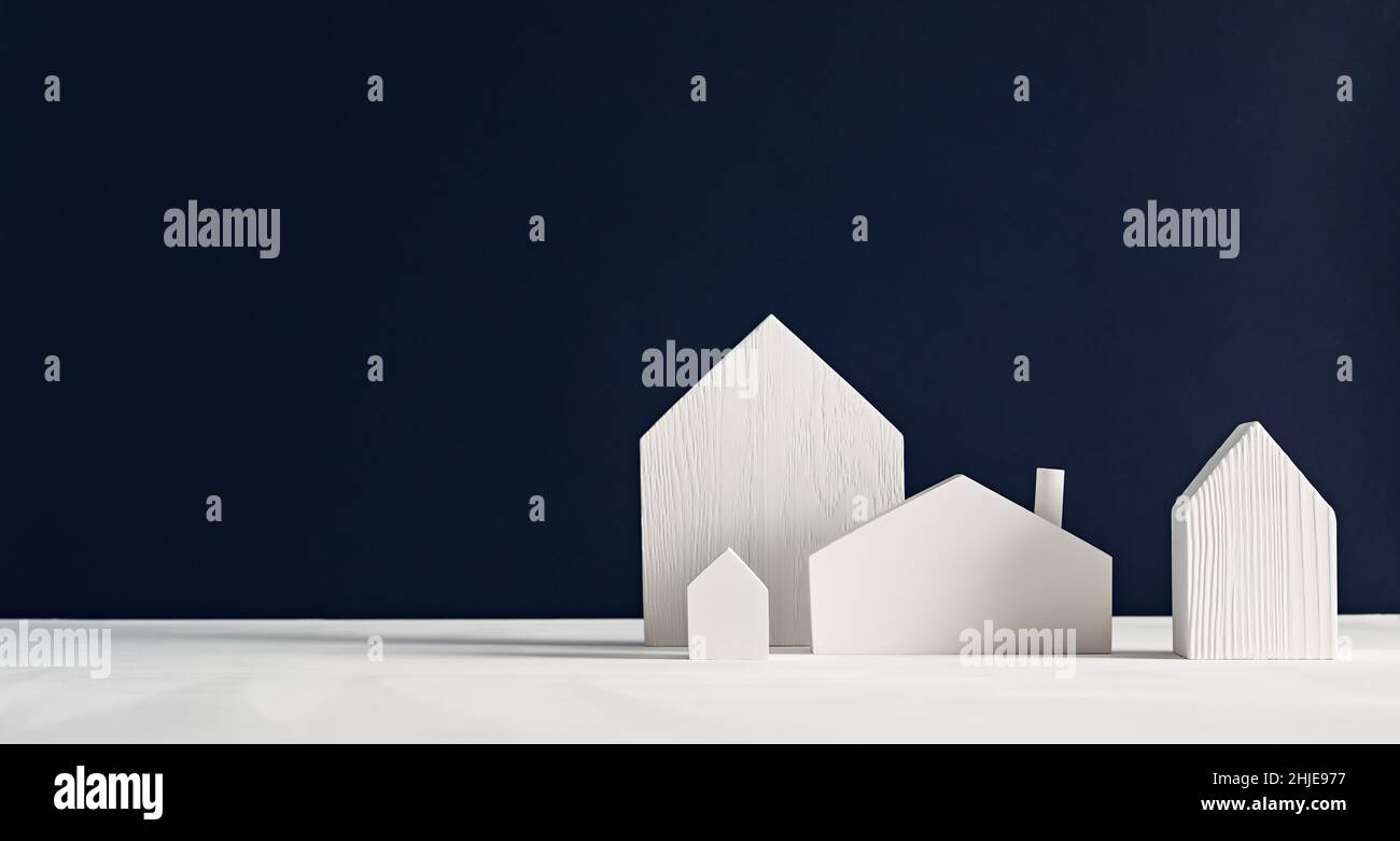 Piccole case giocattolo bianche in legno su sfondo nero. Design minimalista decorativo scandinavo Foto Stock