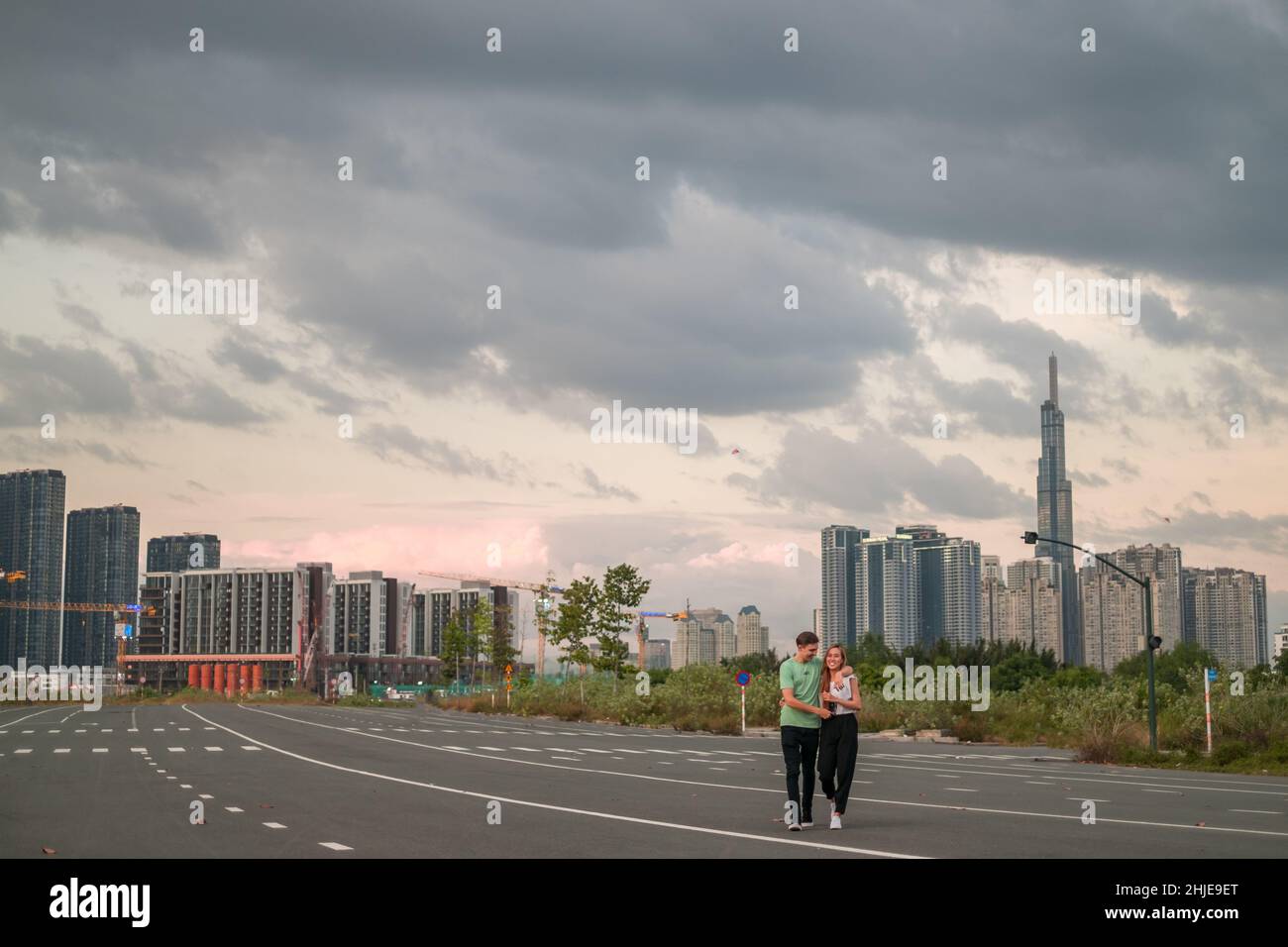 Una giovane coppia adorabile che cammina sulla strada della grande città al tramonto. Ragazzo e ragazza. Amore e felicità. Grattacieli sullo sfondo Foto Stock