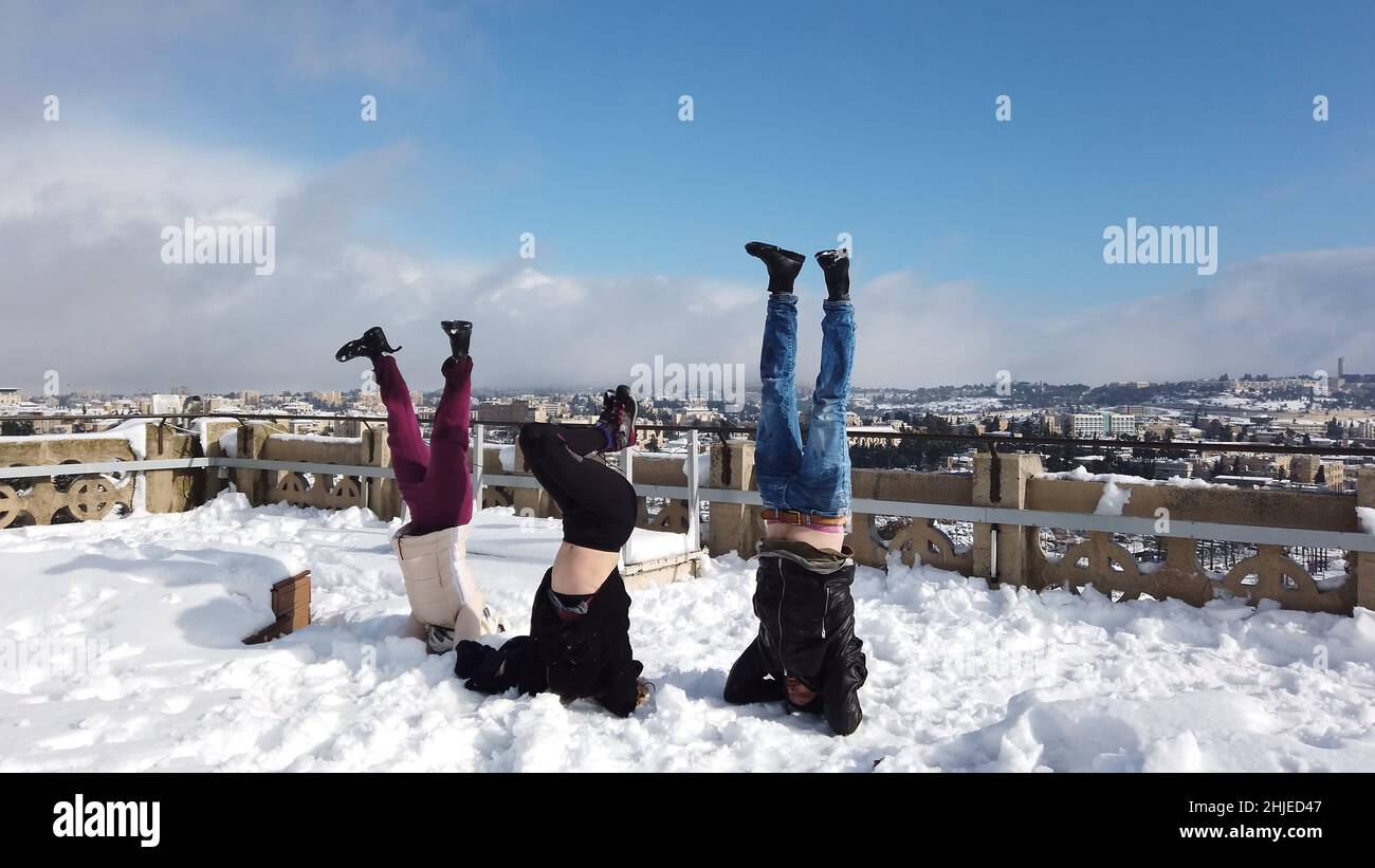 I giovani israeliani fanno una testa mentre si godono la nevicata il 27 gennaio 2022 a Gerusalemme, Israele. Gerusalemme è stata coperta dalla neve che ha raggiunto 10 - 20 centimetri (quattro - otto pollici) durante la notte. Foto Stock
