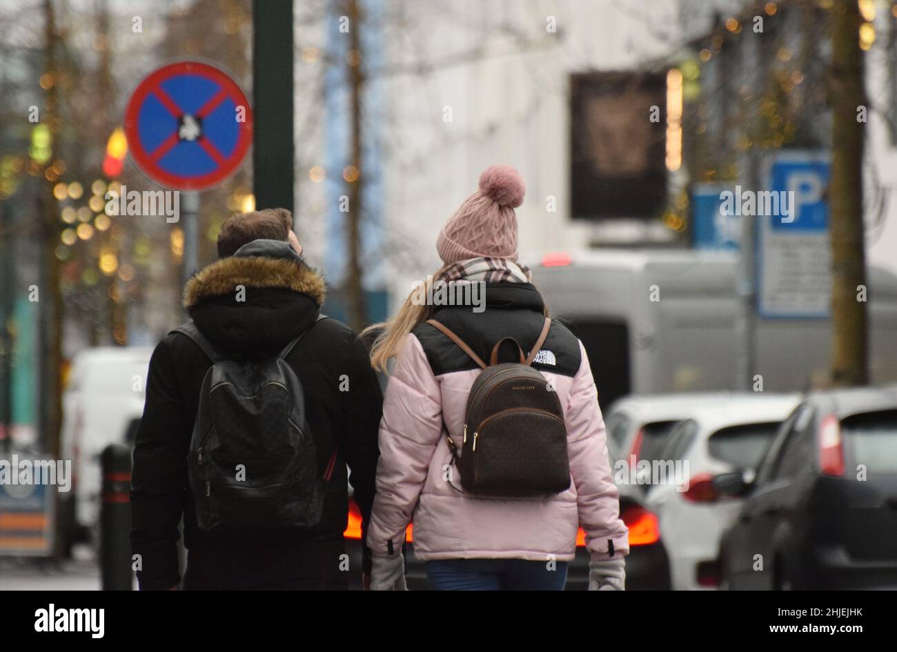 Una giovane coppia di turisti, maschi e femmine che camminano insieme a Reykjavik Islanda a metà inverno indossando abiti per il clima freddo fotografati da dietro Foto Stock