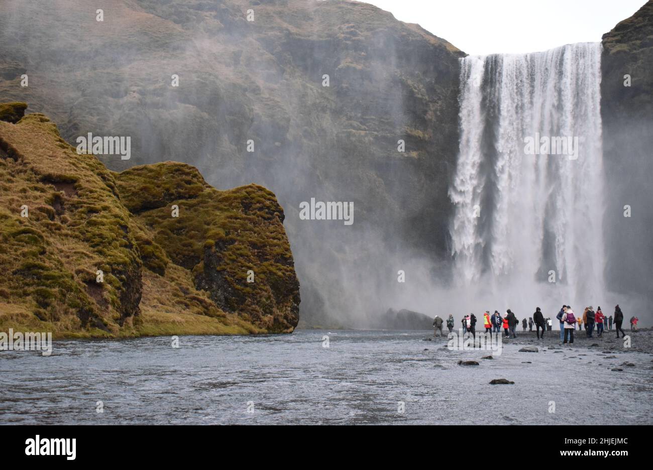 Gennaio 22 Islanda del Sud Un gruppo di turisti che visitano la famosa cascata islandese, Skogafoss. La gente è oscesa dall'enorme cascata alle loro spalle Foto Stock