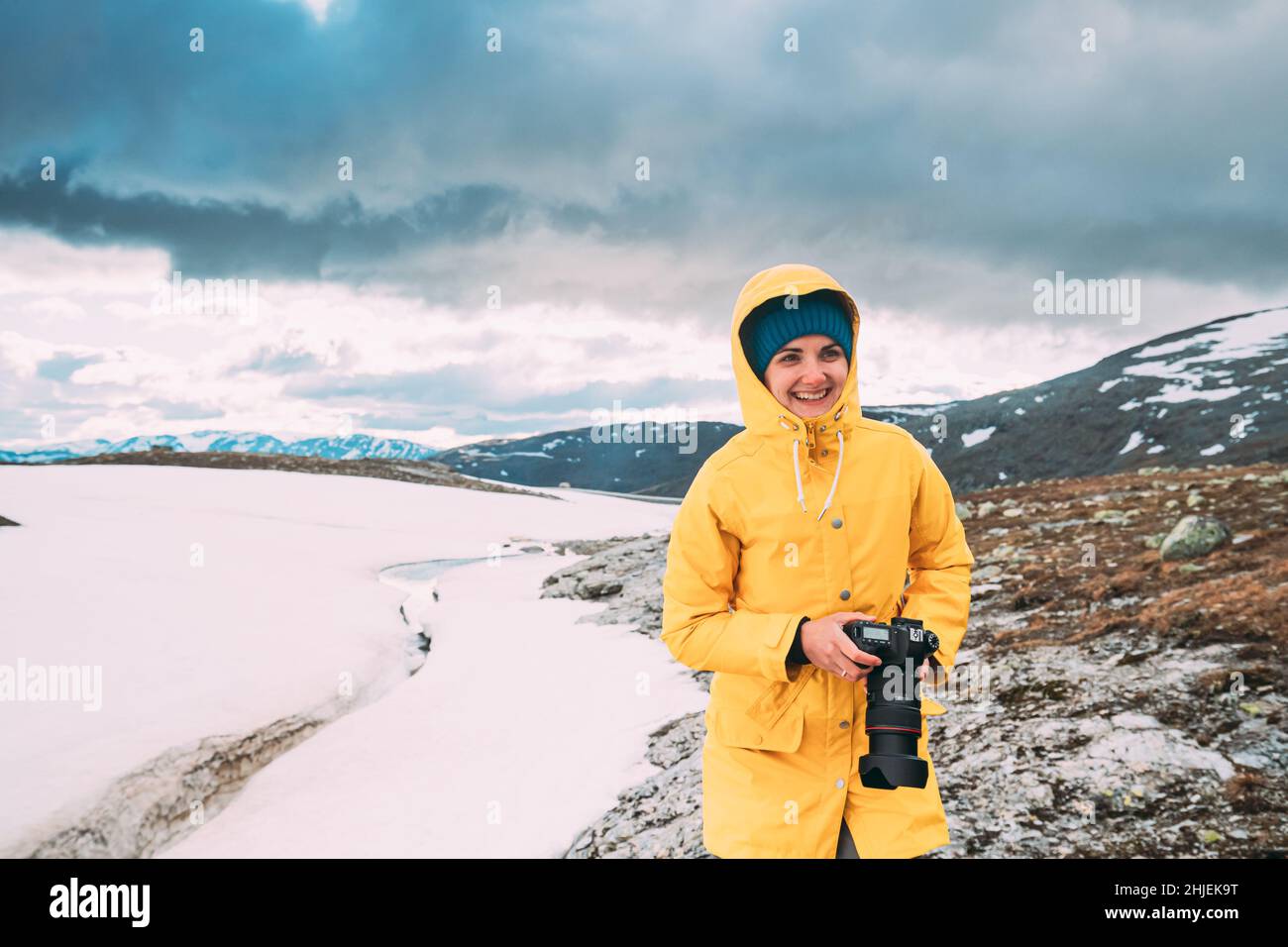 Aurlandsfjellet, Norvegia. Felice giovane donna Tourist Traveler fotografo con fotocamera Camminare vicino a Aurlandsfjellet Scenic Percorso Road. Uno stile di vita attivo Foto Stock