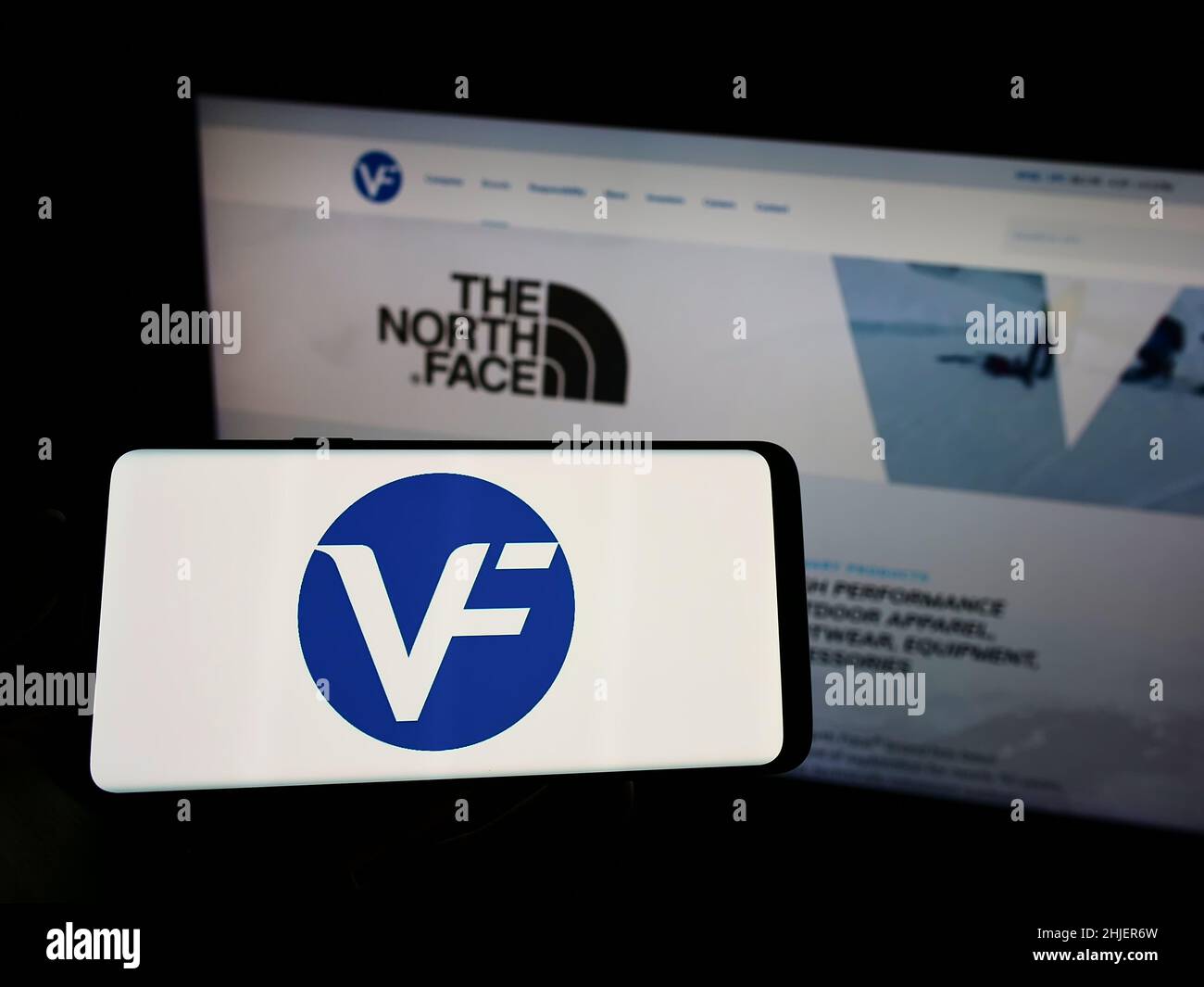 Persona che tiene il cellulare con il logo della società americana di abbigliamento VF Corporation sullo schermo di fronte al sito web aziendale. Mettere a fuoco sul display del telefono. Foto Stock